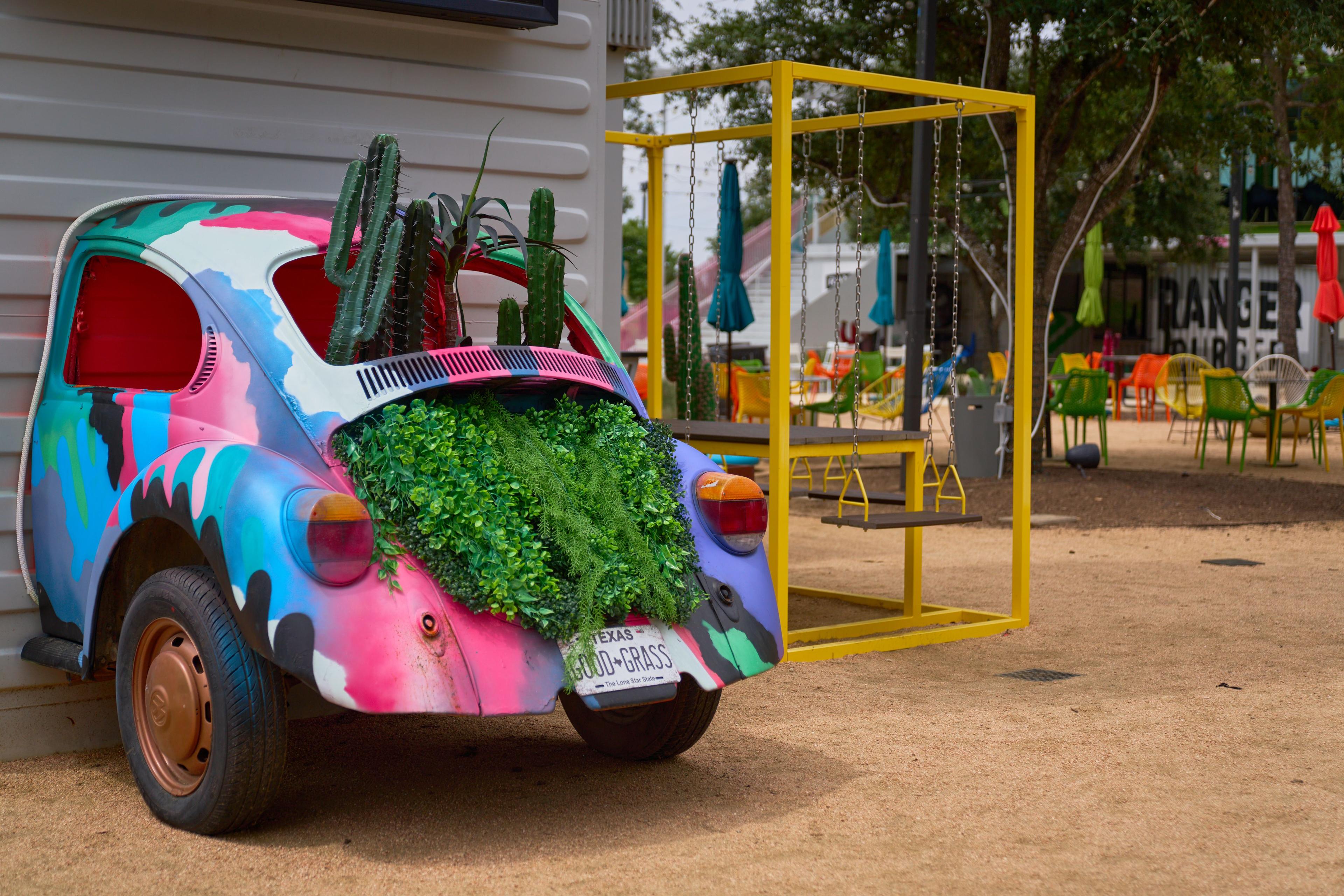 Brightly painted vintage car planted with greenery in a colorful outdoor play area — Hospitality & leisure photography, Austin A brightly painted vintage car planted with greenery in a colorful outdoor play area.