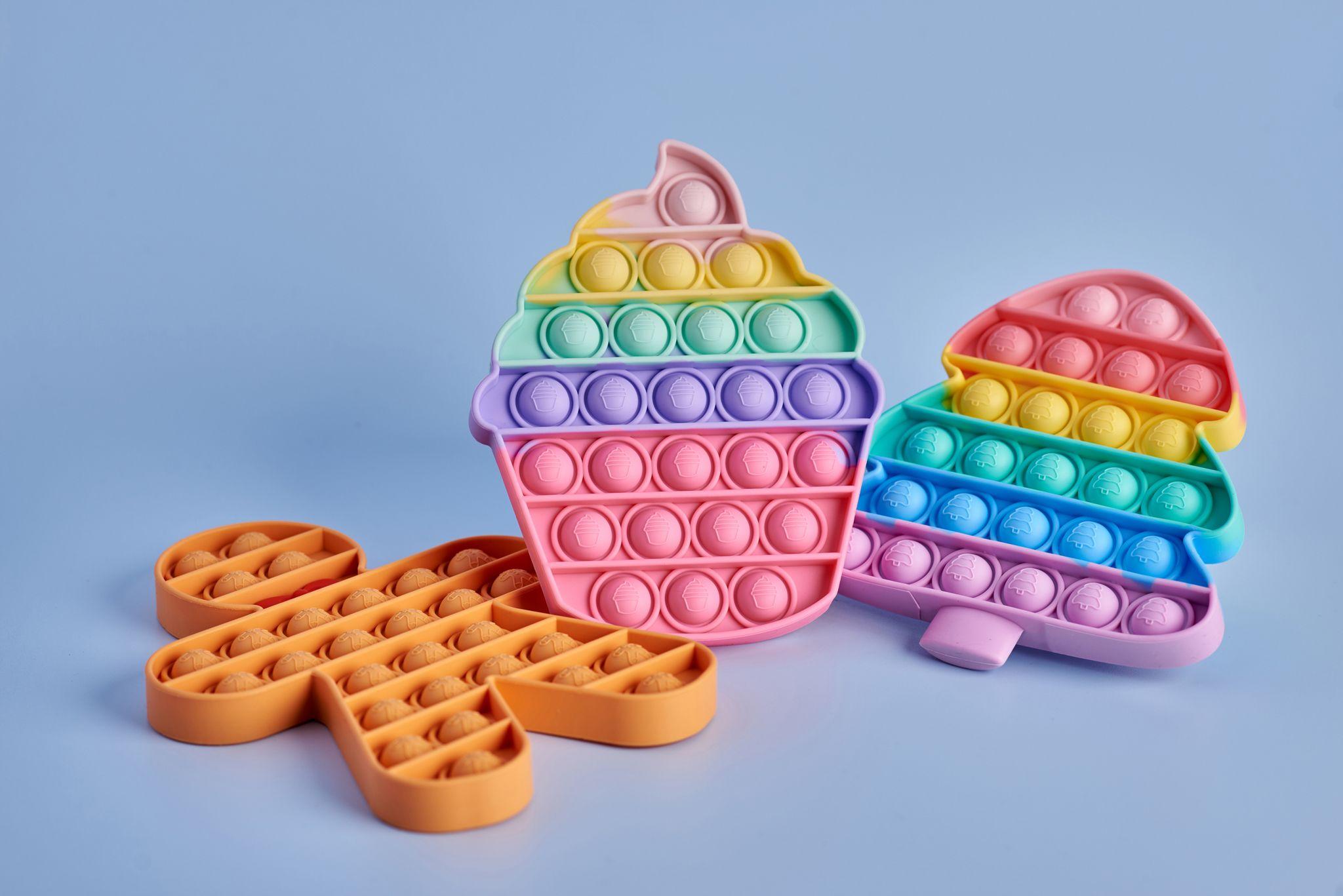 Pastel silicone pop-it fidget toys arranged on a pale blue background — Product photography, Austin Pastel silicone pop-it fidget toys arranged on a pale blue background.
