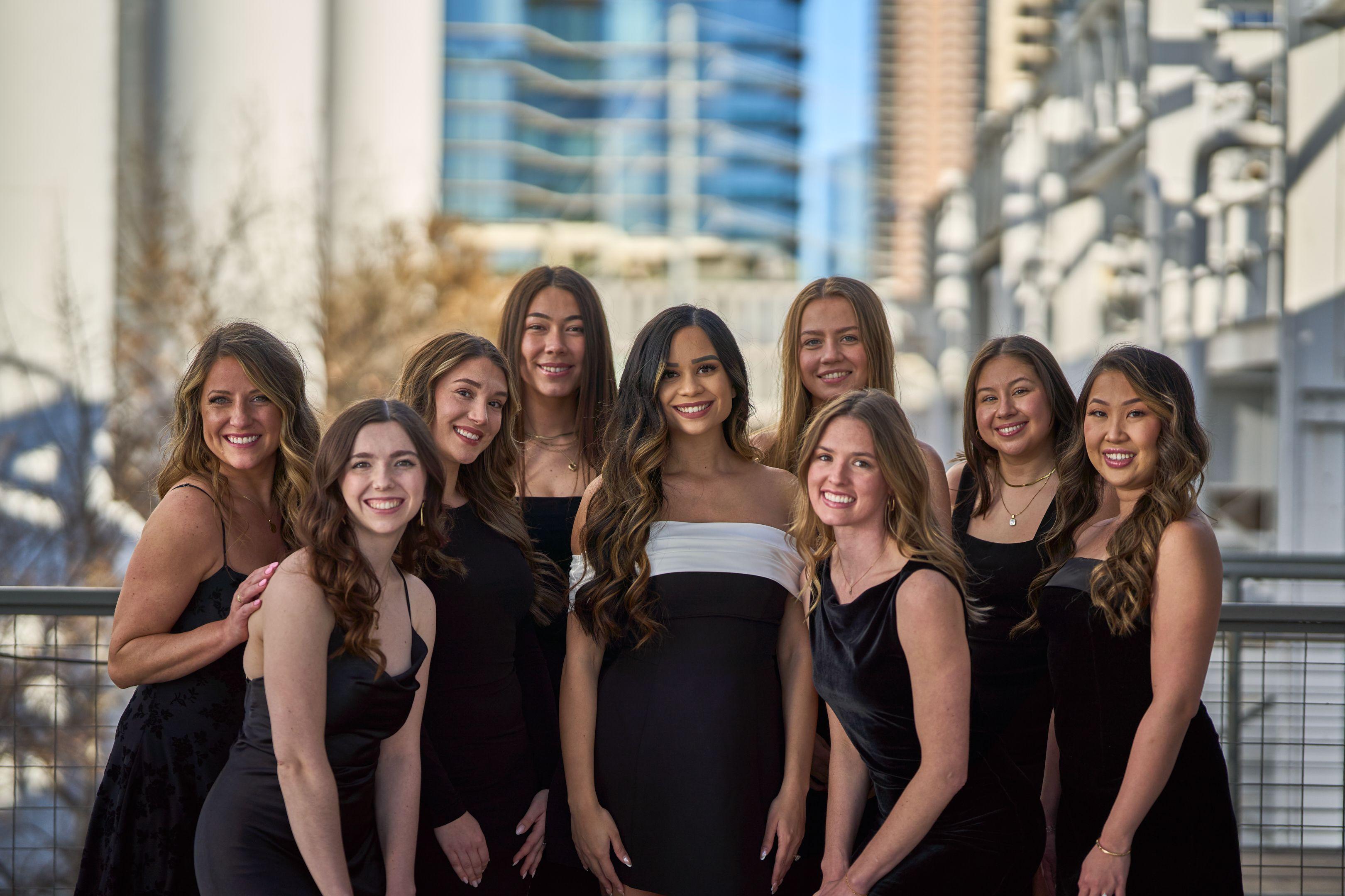 Six friends in black dresses standing shoulder to shoulder against high-rise towers — Bachelor & Bachelorette photography, Austin Six friends in black dresses standing shoulder to shoulder against high-rise towers.