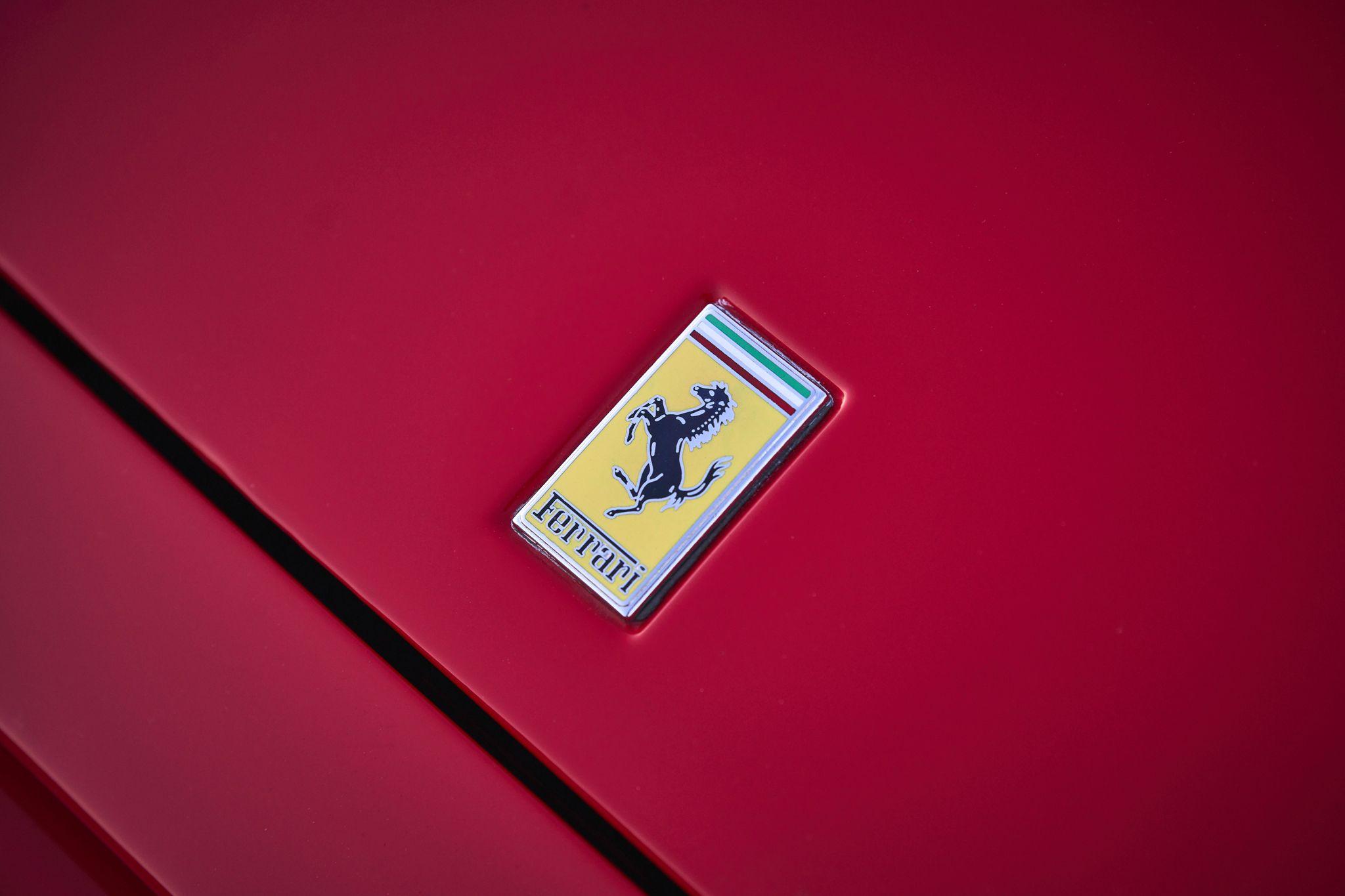 Close detail of the Ferrari prancing horse badge on a red body panel — Automotive photography, Austin A close detail of the Ferrari prancing horse badge on a red body panel.