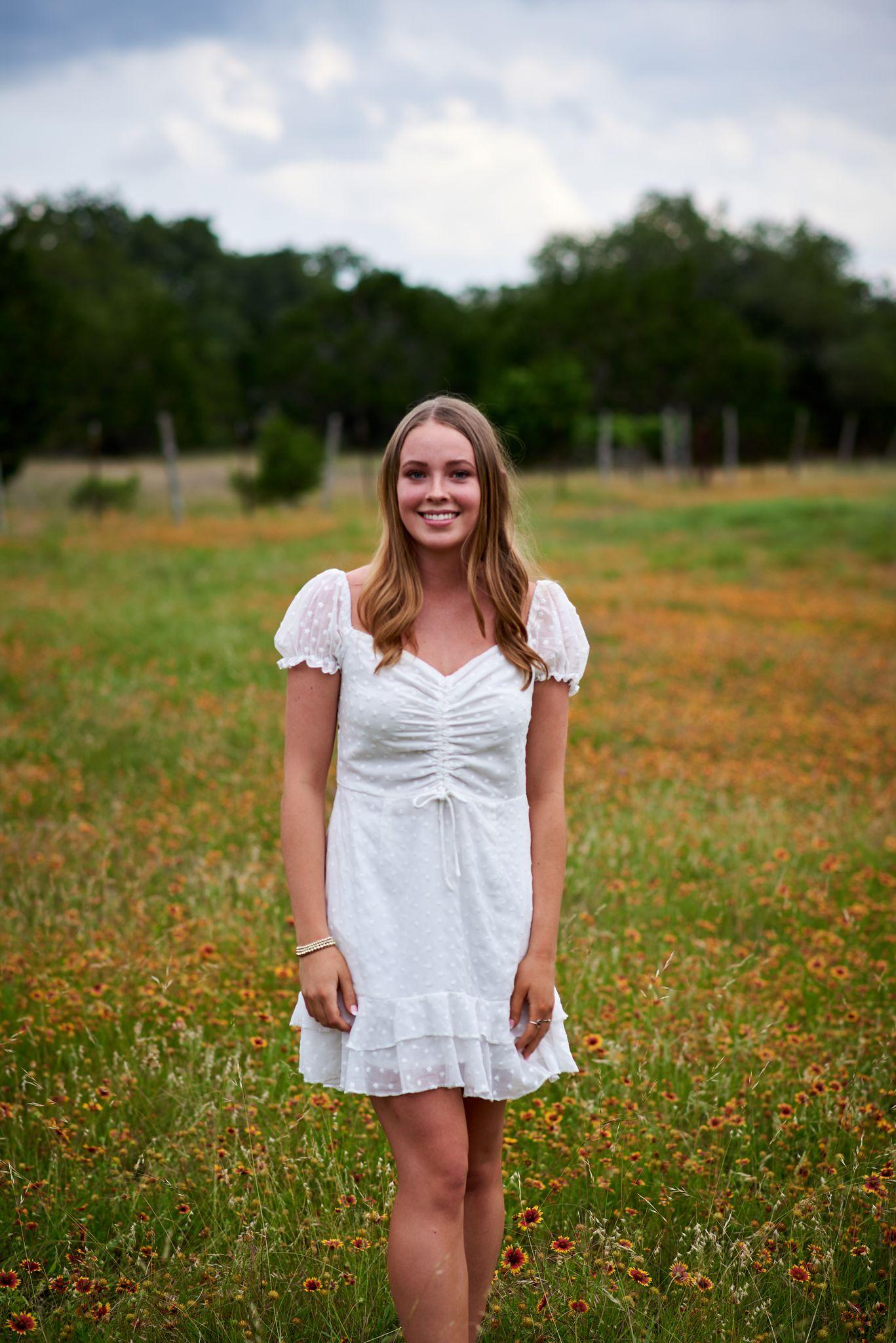 Girl in a white dress standing in a wide meadow at golden hour — Kids Portraits photography, Austin A girl in a white dress standing in a wide meadow at golden hour.