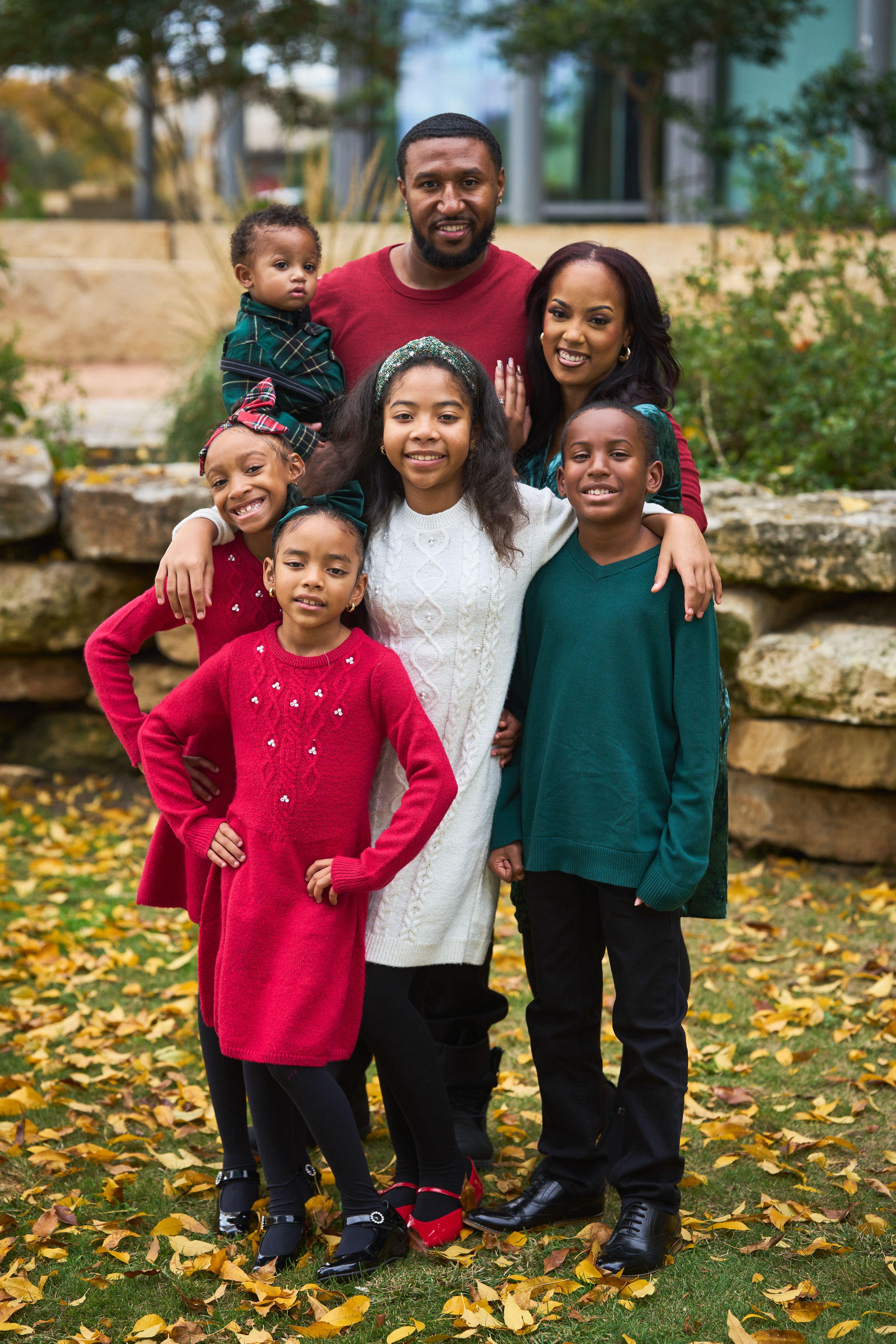 Family in red and green posed together on a path covered in autumn leaves — Seasonal Christmas & Fall photography, Austin A family in red and green posed together on a path covered in autumn leaves.
