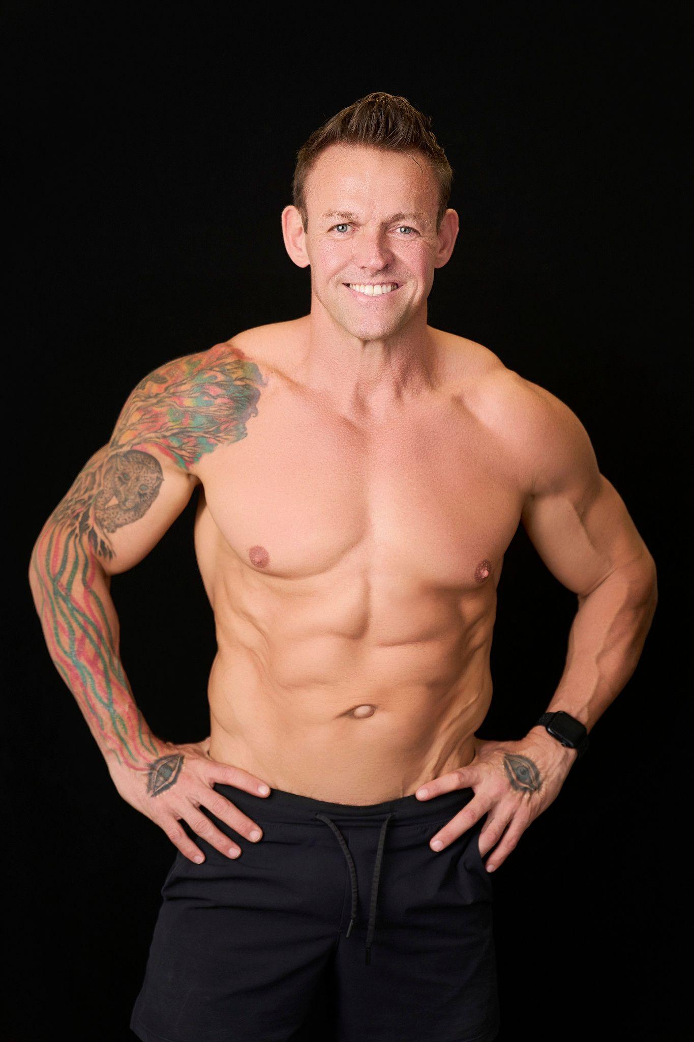 Muscular tattooed man photographed shirtless against a black studio background — Photo retouching, Austin A muscular tattooed man photographed shirtless against a black studio background.