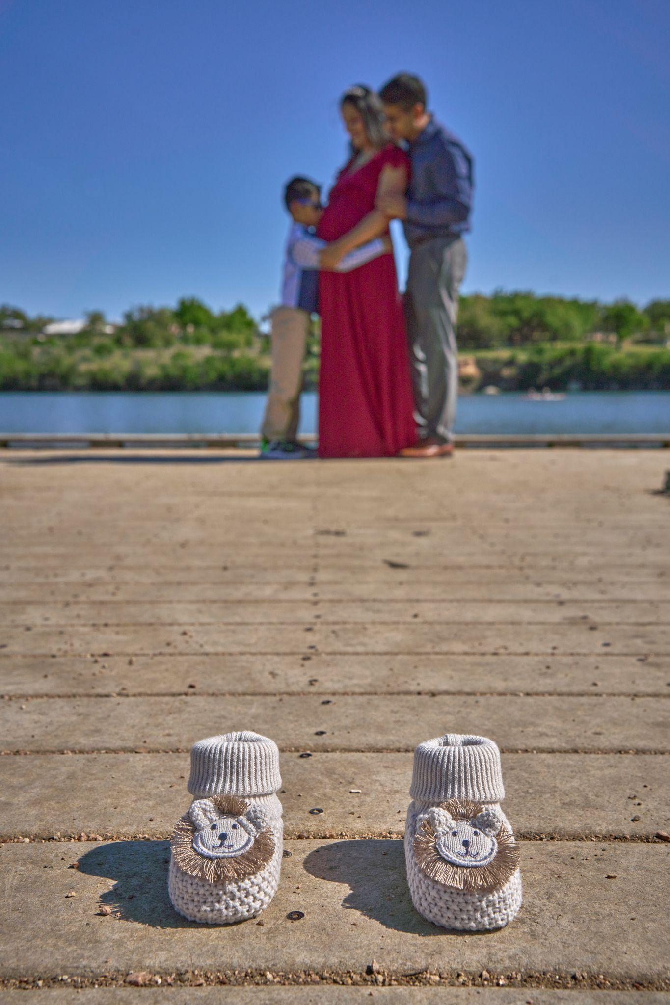Expectant couple on the Brushy Creek boardwalk with a pair of knitted baby booties set — Brushy Creek Lake Park photography, Austin An expectant couple on the Brushy Creek boardwalk with a pair of knitted baby booties set on the boards in front of them