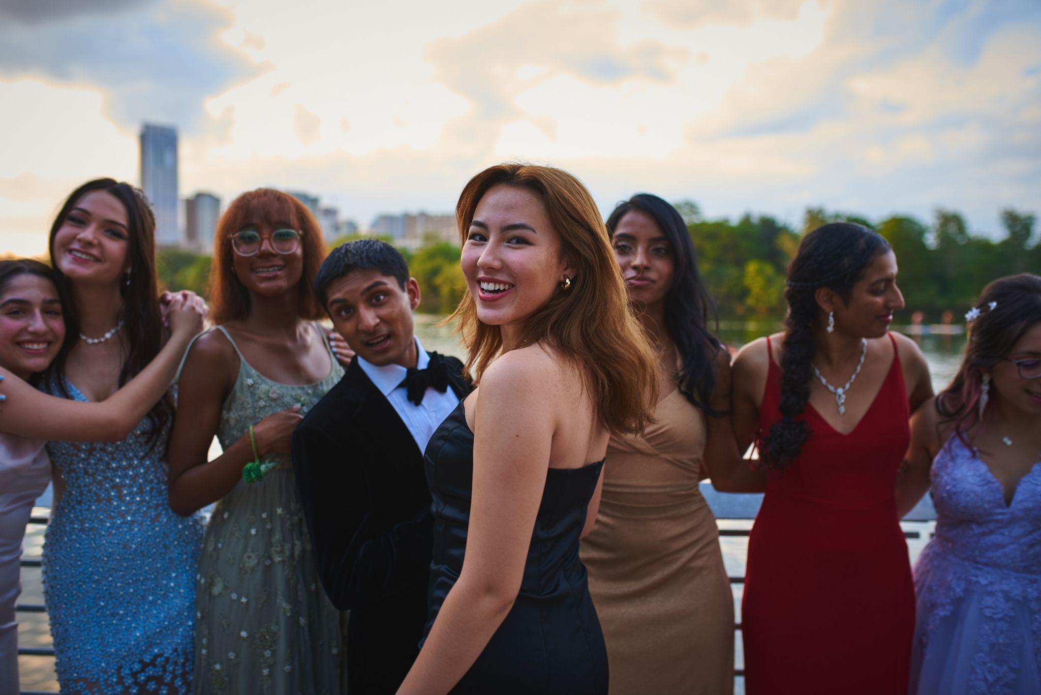 Group of friends in prom dresses and tuxedos looking back over their shoulders — Austin Boardwalk photography, Austin A group of friends in prom dresses and tuxedos looking back over their shoulders.