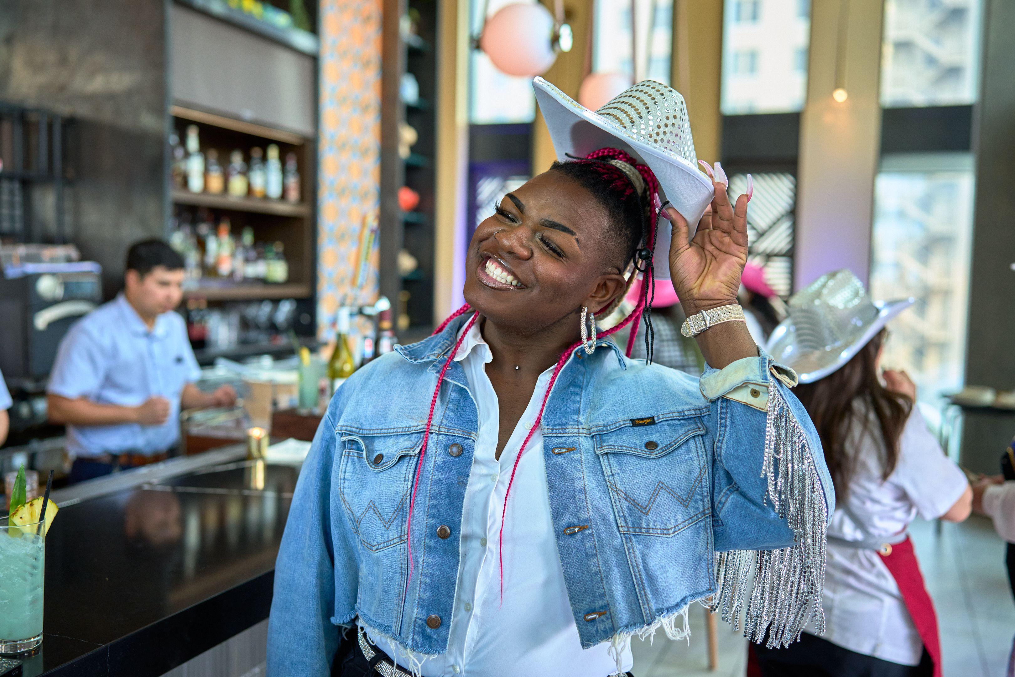 Guest in a denim jacket laughing as she balances a white cowboy hat on her head — Business Parties photography, Austin A guest in a denim jacket laughing as she balances a white cowboy hat on her head.