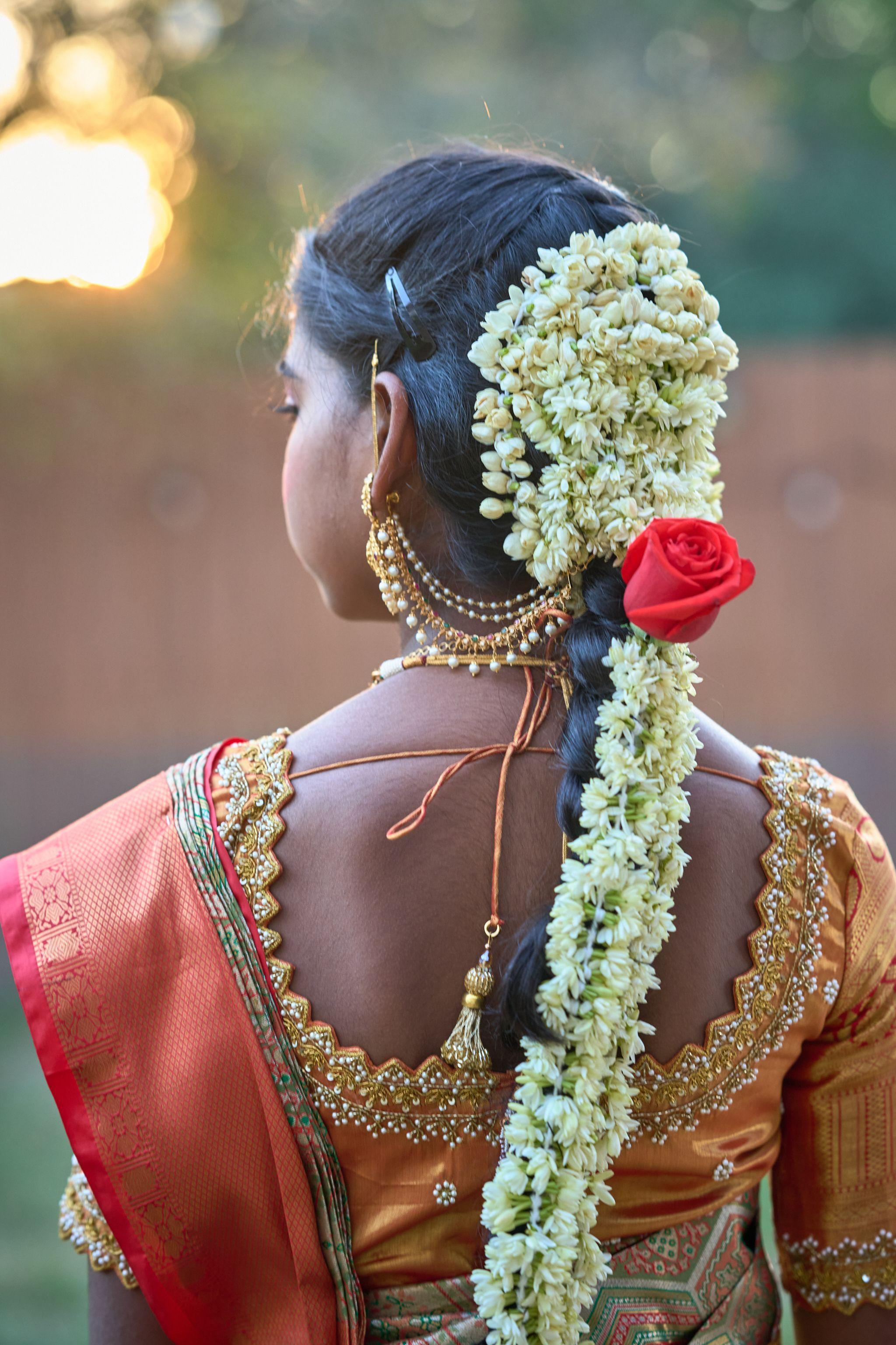 Back of a young woman's head showing a braided hairstyle dressed with jasmine and a red rose — Religious Ceremonies photography, Austin The back of a young woman's head showing a braided hairstyle dressed with jasmine and a red rose.