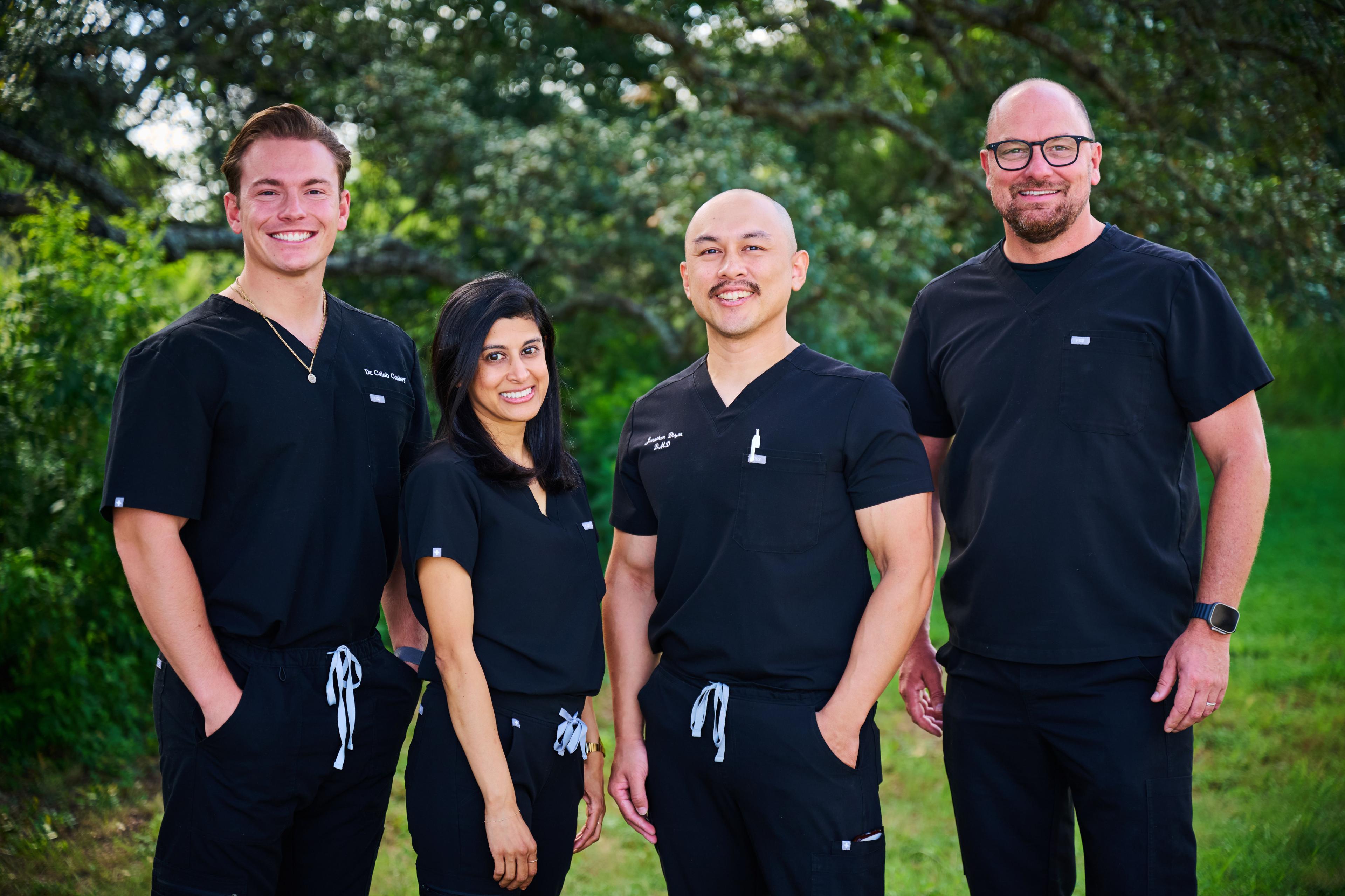 Practice team in dark scrubs standing together outdoors among trees — Medical team photography, Austin Practice team in dark scrubs standing together outdoors among trees