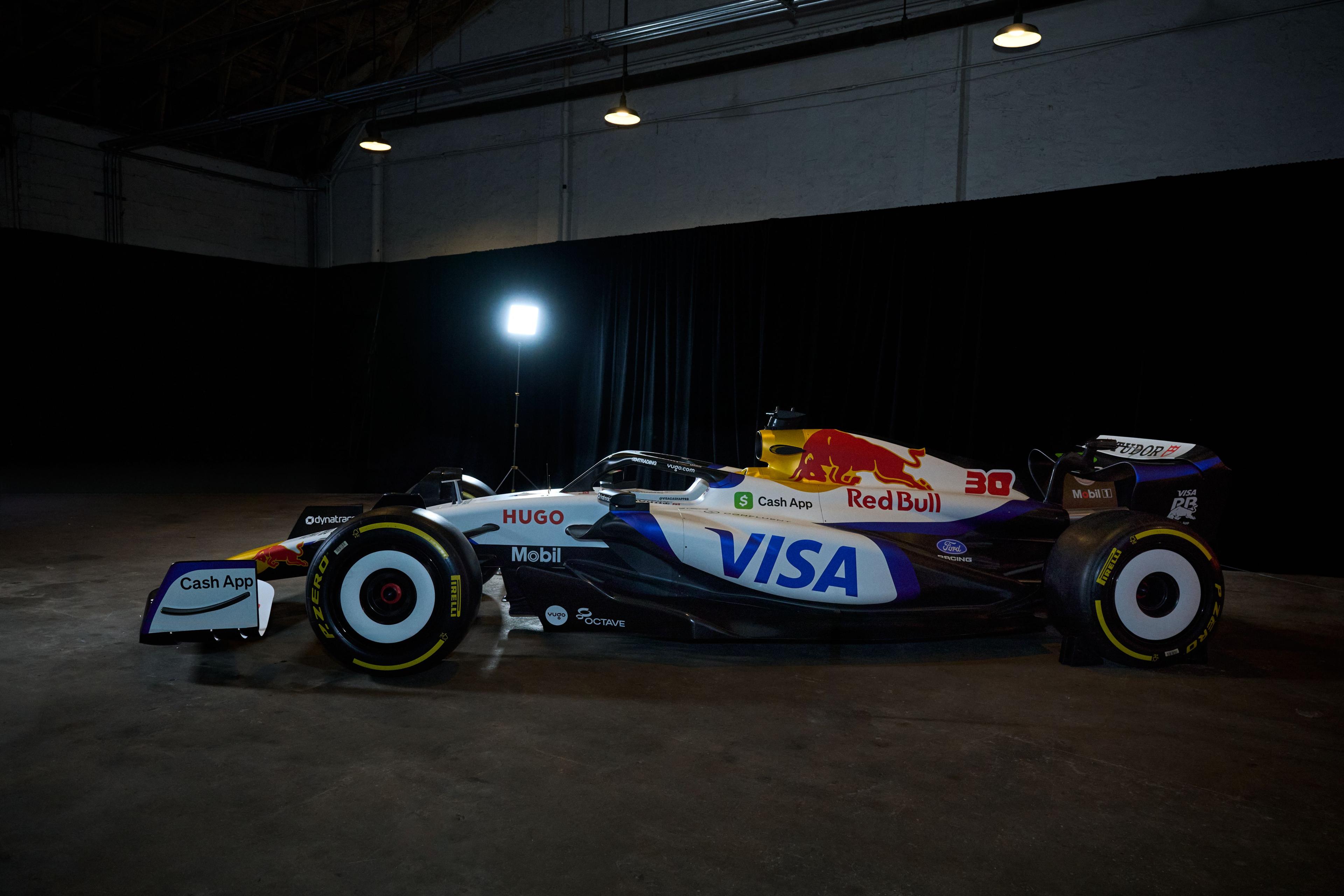 Visa and Red Bull Formula 1 show car lit in a dark warehouse — Brand activation photography, Austin A Visa and Red Bull Formula 1 show car lit in a dark warehouse.
