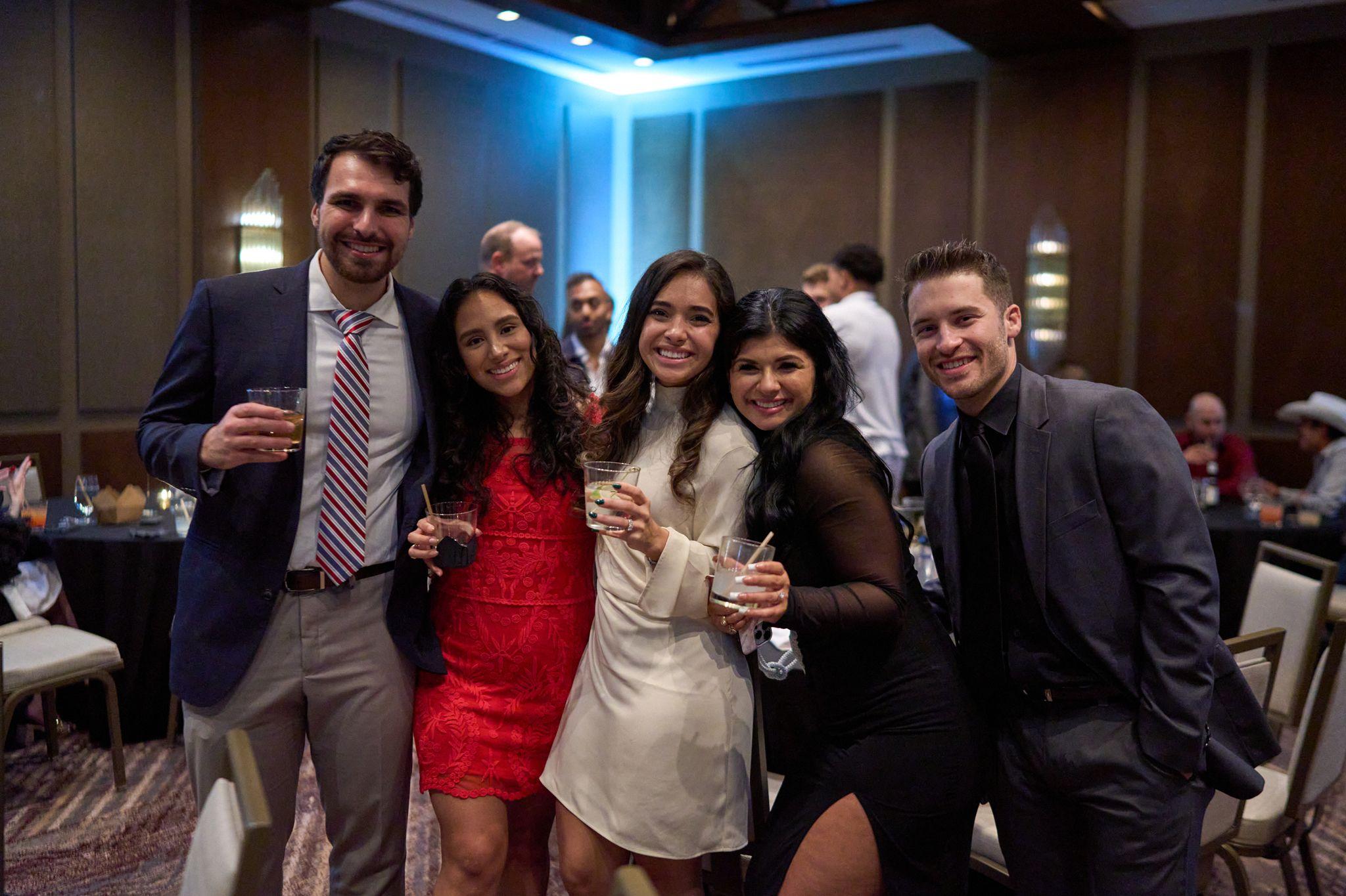 Guests posing together with drinks at an indoor party lit blue — Business Parties photography, Austin Guests posing together with drinks at an indoor party lit blue.