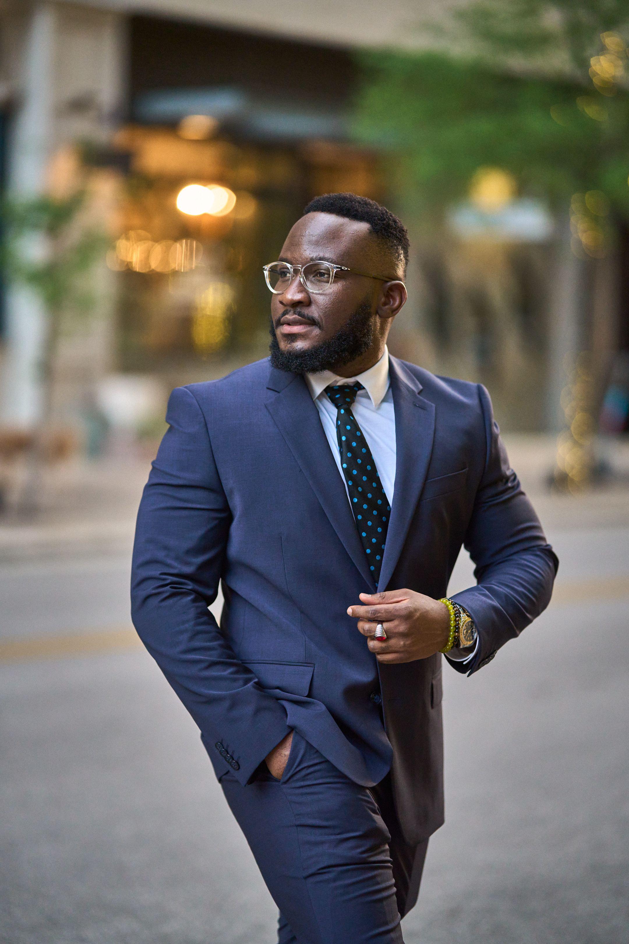 Man in a navy suit walking along a downtown street — Headshot photography, Austin A man in a navy suit walking along a downtown street.