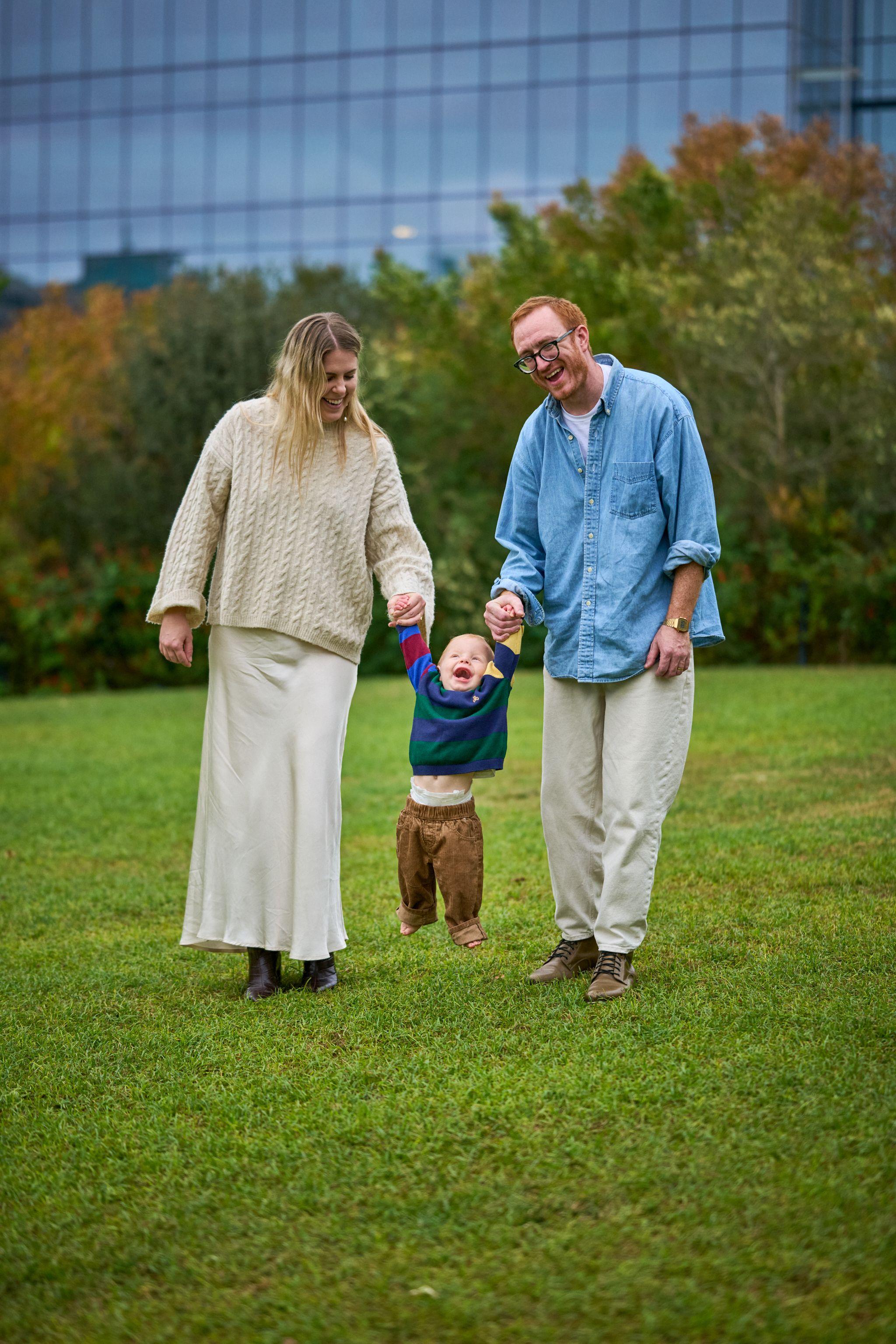 Parents walking a toddler between them across the park lawn — Waterloo Park photography, Austin Parents walking a toddler between them across the park lawn.