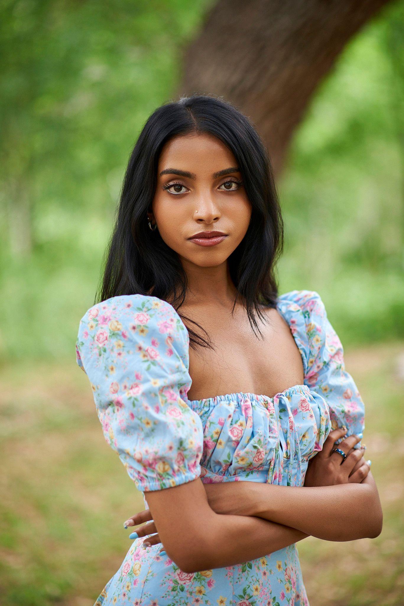 Woman in a blue floral puff-sleeve top standing with arms crossed under a tree — Photo retouching, Austin A woman in a blue floral puff-sleeve top standing with arms crossed under a tree.