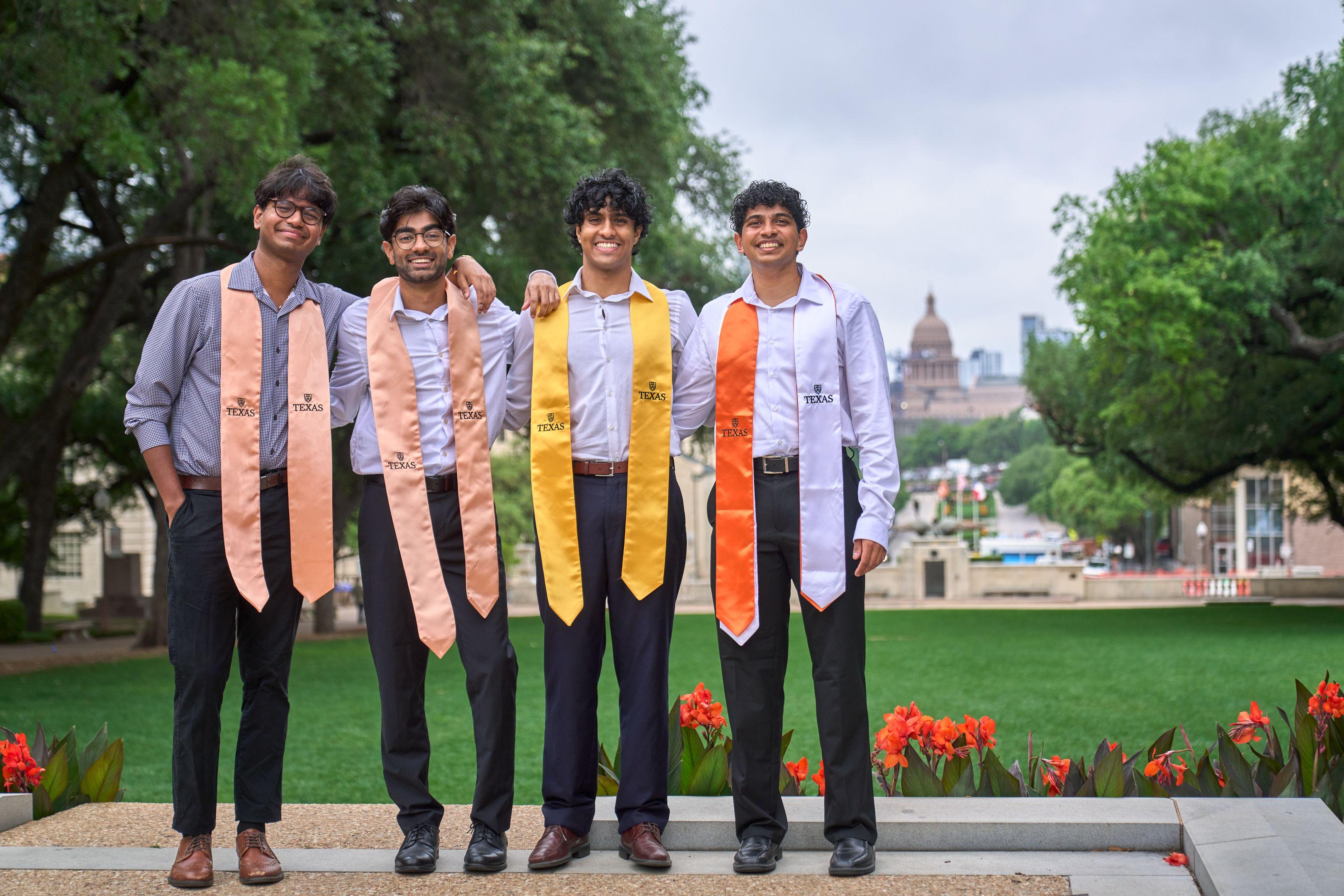 Three graduates in orange and gold stoles standing on the mall, the Capitol in the distance — UT Austin photography, Austin Three graduates in orange and gold stoles standing on the mall, the Capitol in the distance.