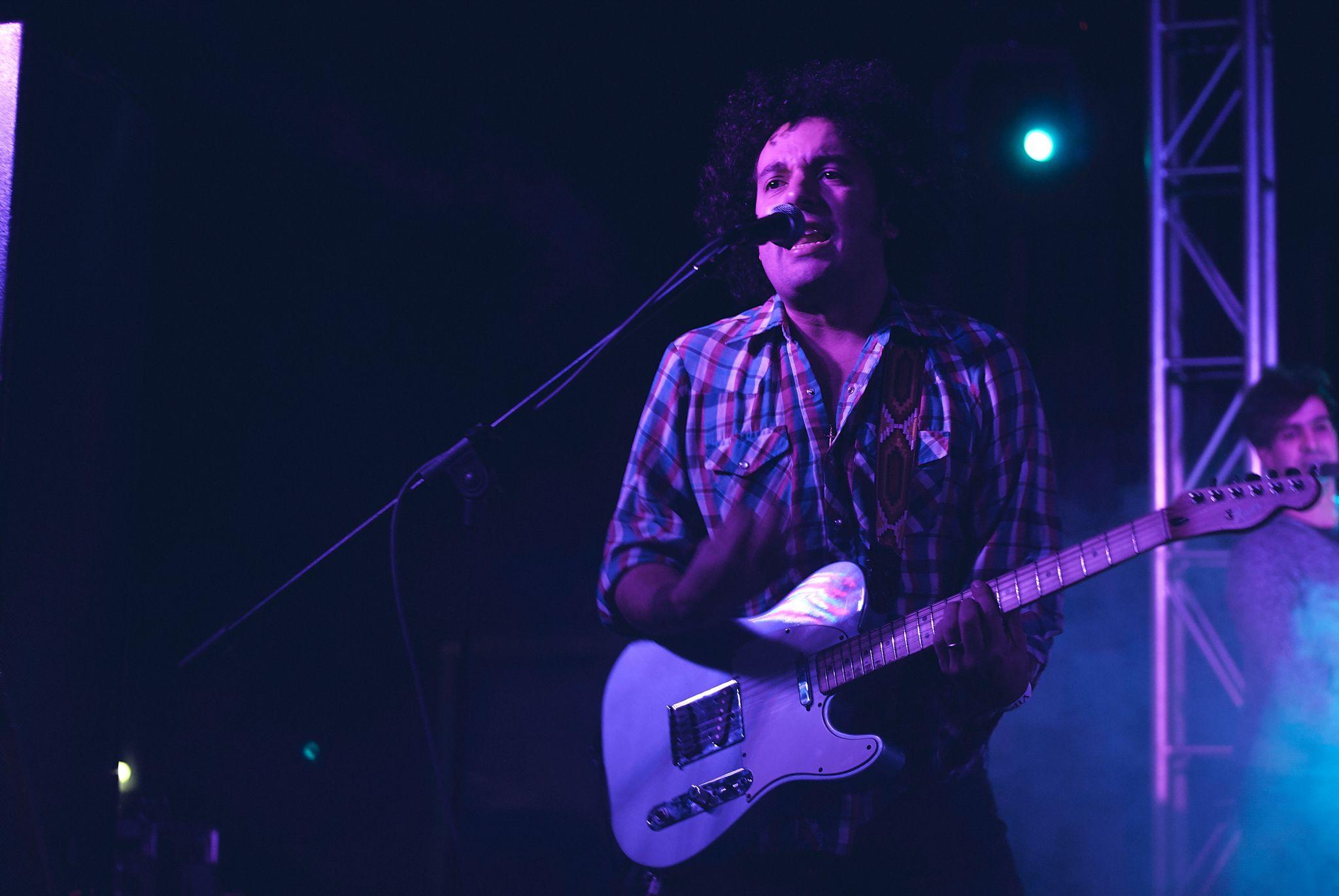 Guitarist playing a blue electric guitar under purple stage light — Live music photography, Austin A guitarist playing a blue electric guitar under purple stage light.