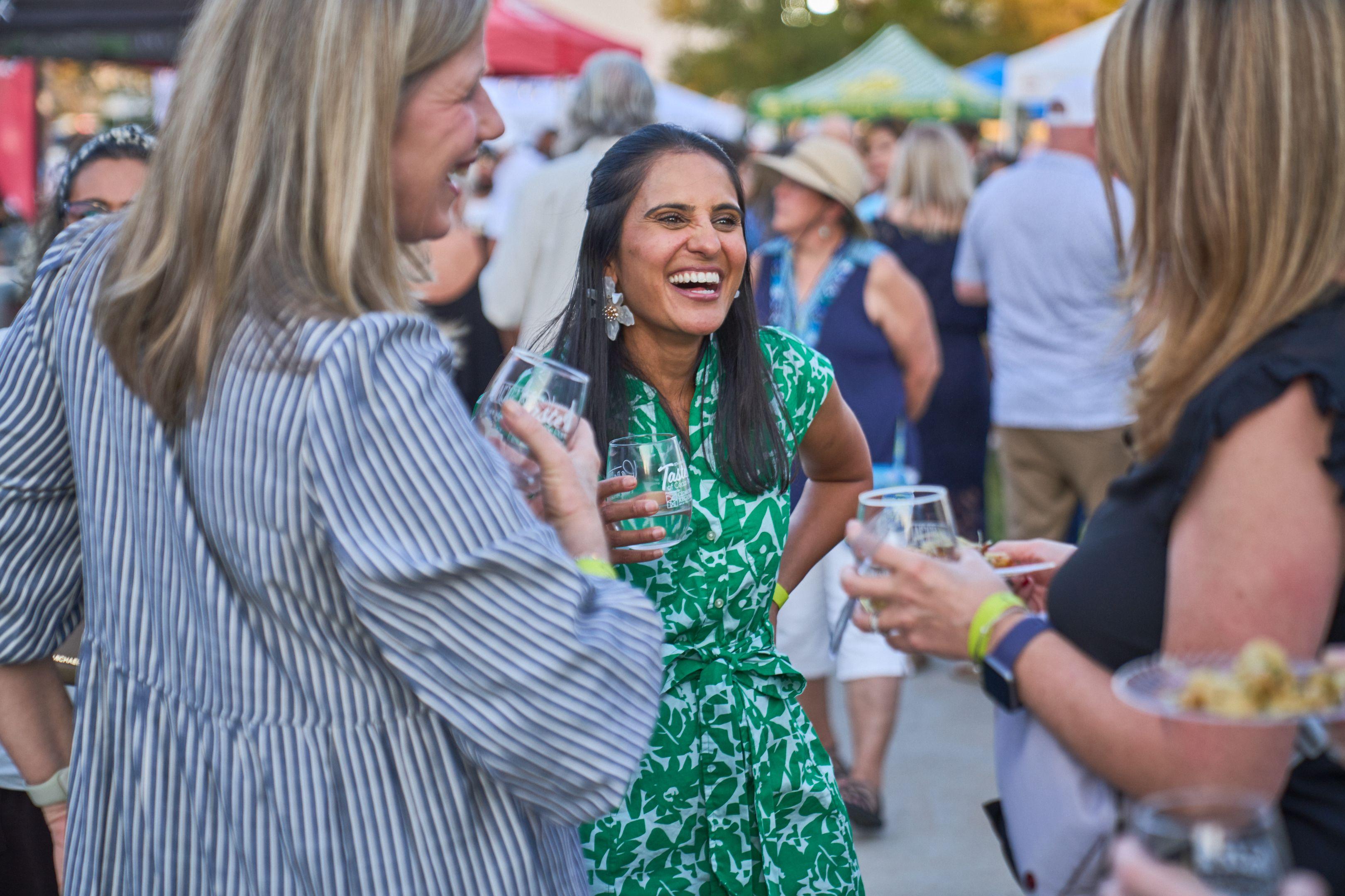 Two women laughing together with drinks at an outdoor tasting event — Festival photography, Austin Two women laughing together with drinks at an outdoor tasting event.