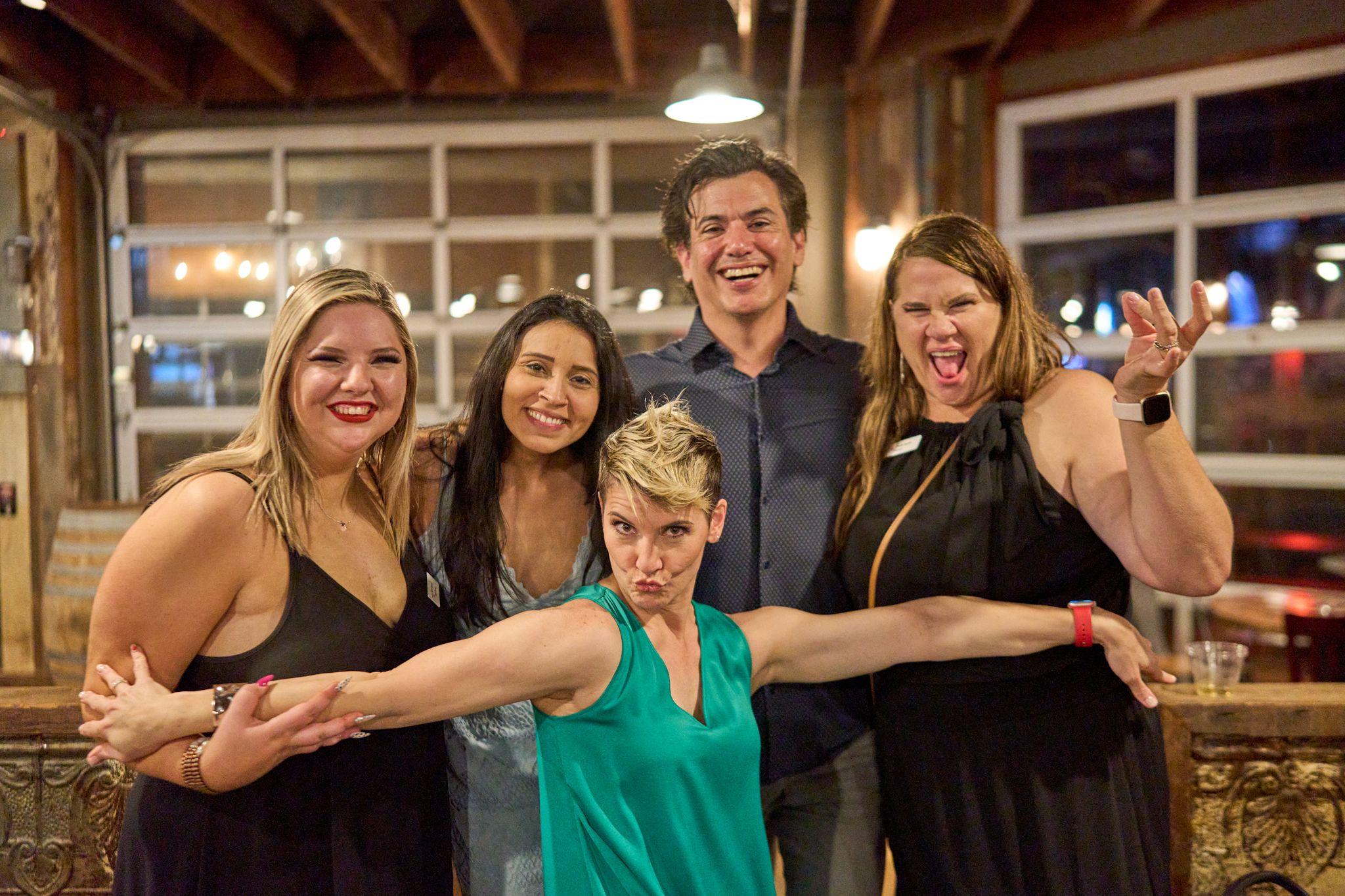 Group of colleagues pulling faces together for a photo at a bar, one leaning in front — Business Parties photography, Austin A group of colleagues pulling faces together for a photo at a bar, one leaning in front.