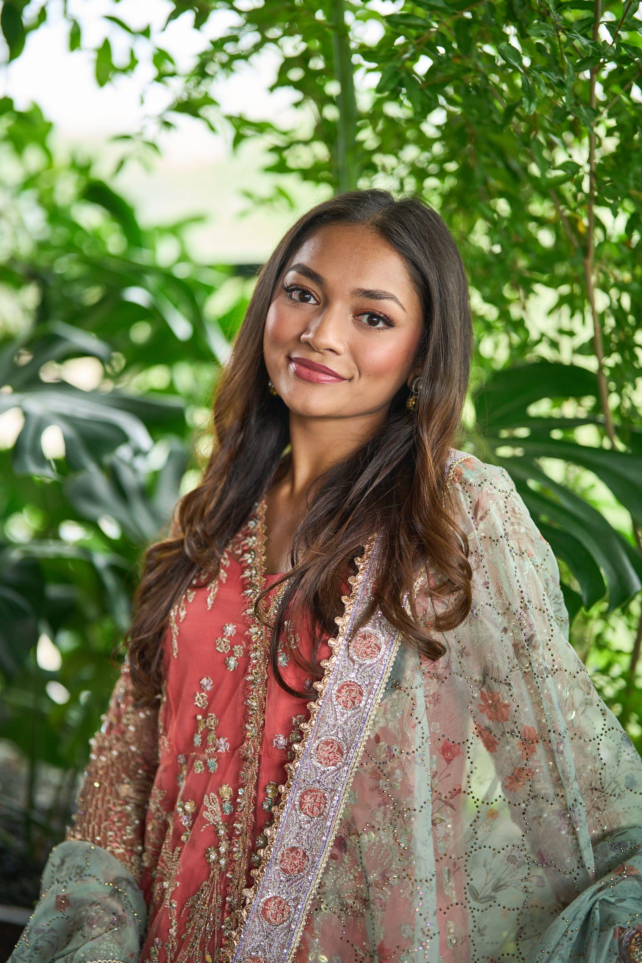 Model in a coral kurta with an embroidered pale green dupatta standing among greenery — Fashion & editorial photography, Austin A model in a coral kurta with an embroidered pale green dupatta standing among greenery.