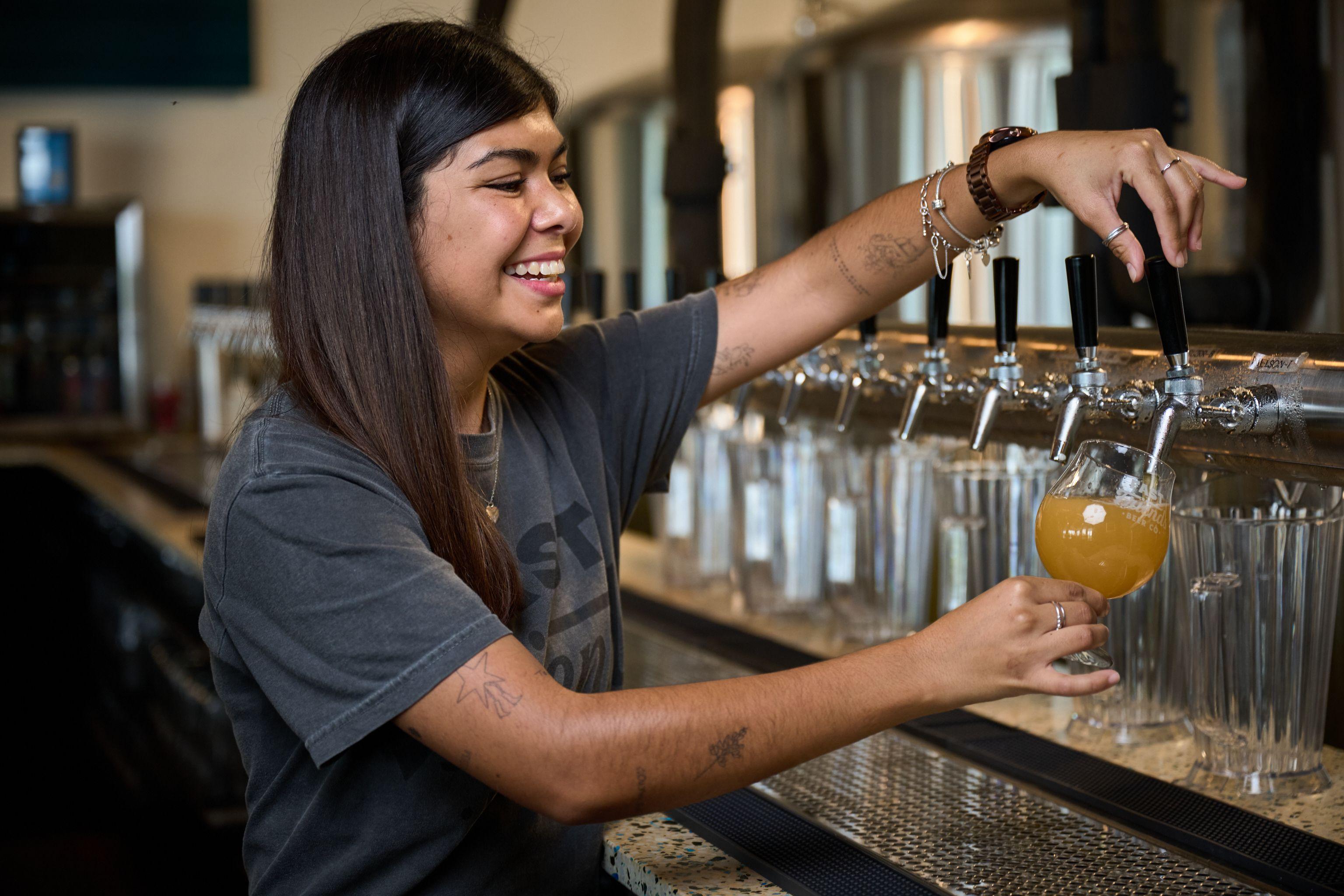 Bartender reaching up for glassware behind the bar — Hospitality & leisure photography, Austin A bartender reaching up for glassware behind the bar.