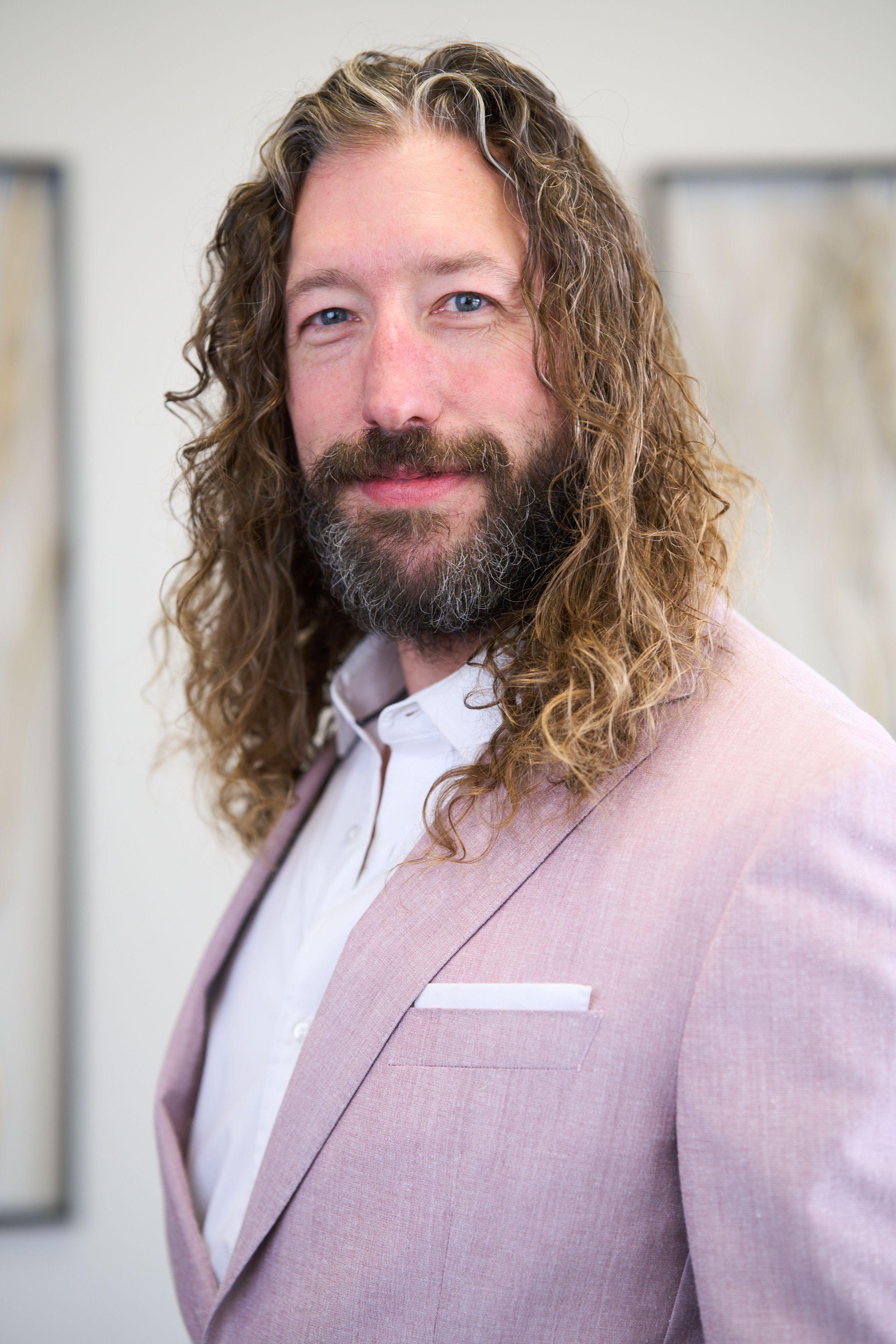 Man with long hair in a pale pink blazer photographed in a clinic interior — Medical team photography, Austin Man with long hair in a pale pink blazer photographed in a clinic interior