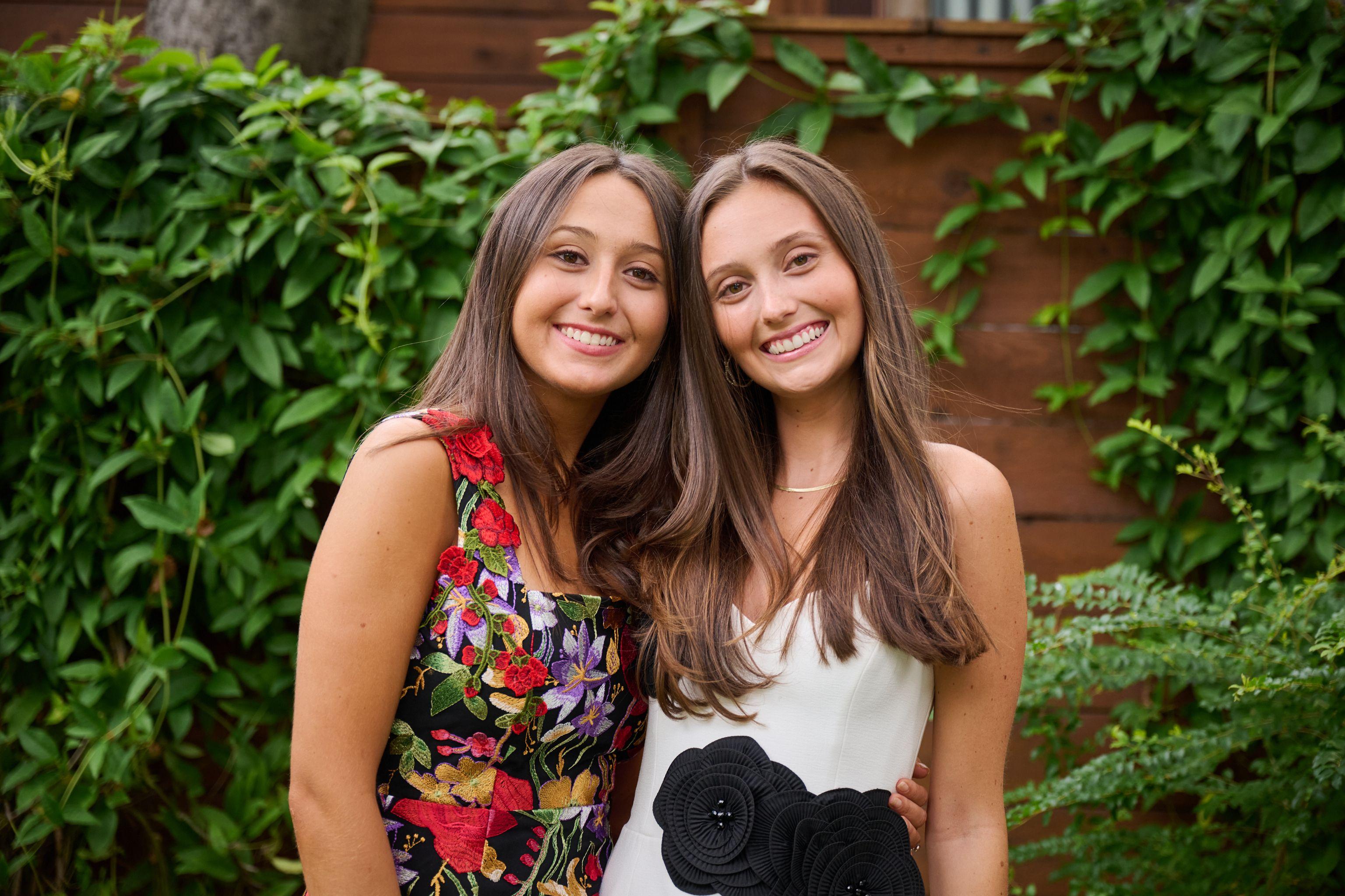 Two young women in floral and black-and-white dresses posed side by side in a garden — Formal Celebrations photography, Austin Two young women in floral and black-and-white dresses posed side by side in a garden.