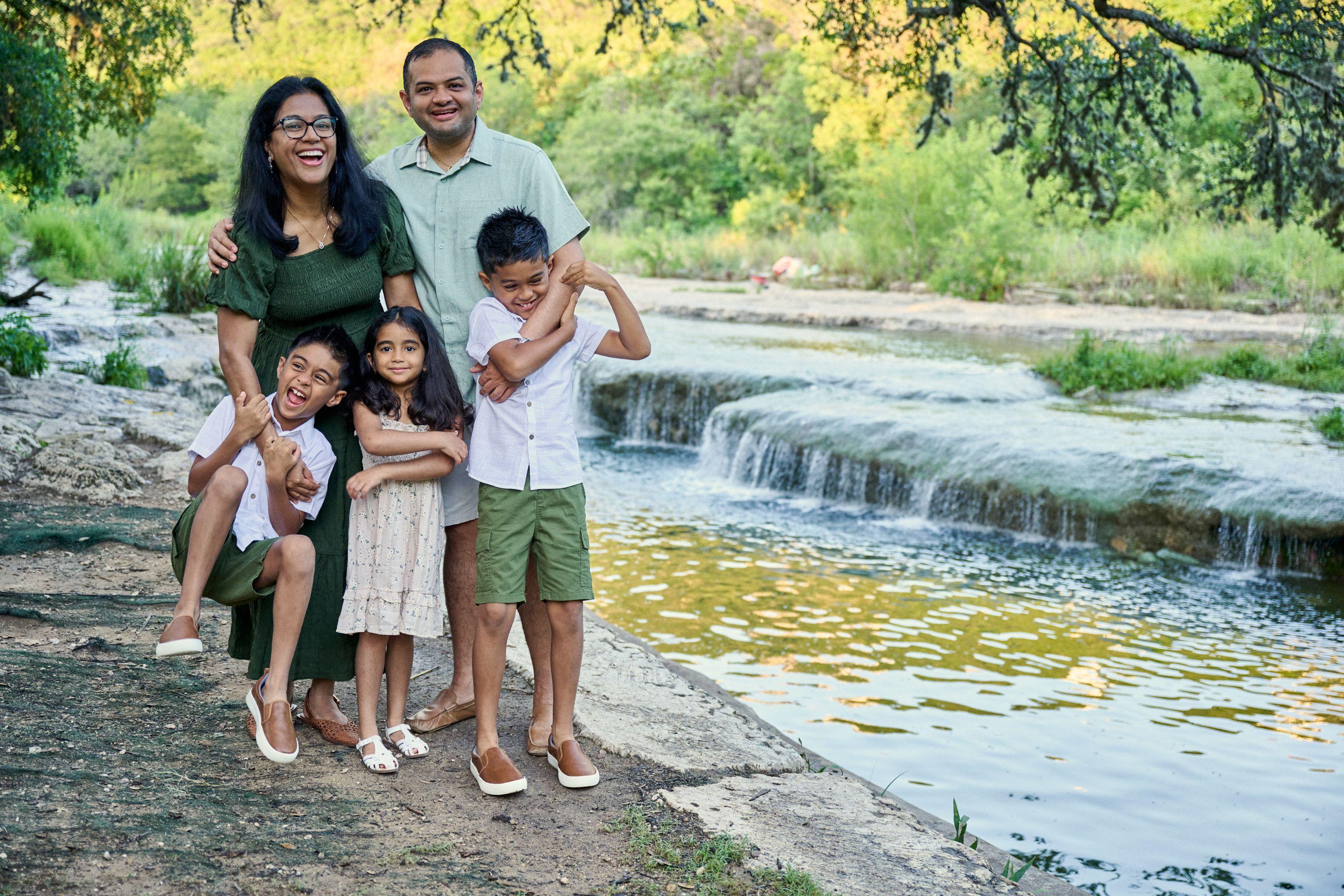 Family posed on the rock ledge above a low creek waterfall — Bull Creek District Park photography, Austin A family posed on the rock ledge above a low creek waterfall.