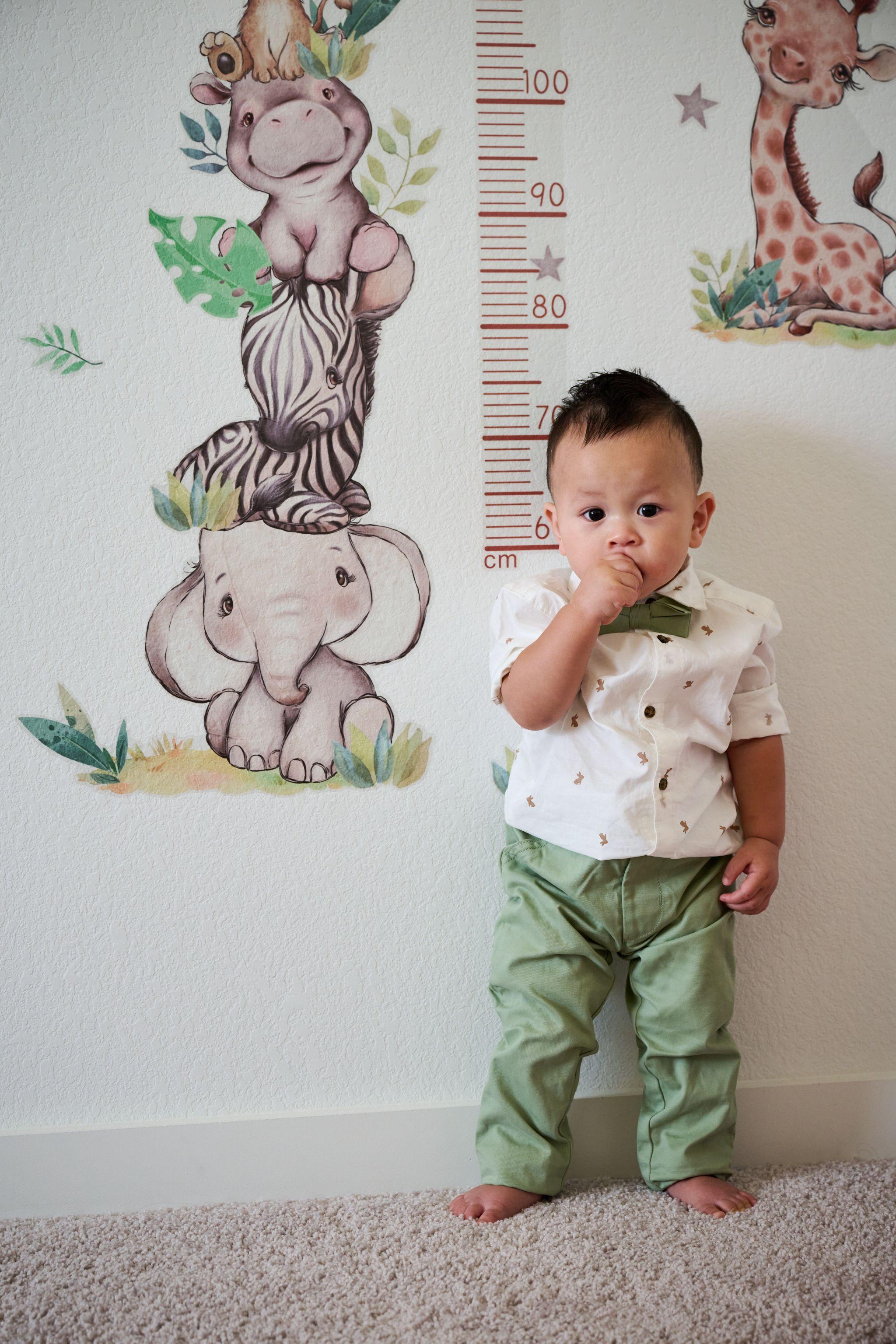 Toddler standing beside a painted jungle growth chart on a nursery wall — Kids Portraits photography, Austin A toddler standing beside a painted jungle growth chart on a nursery wall.