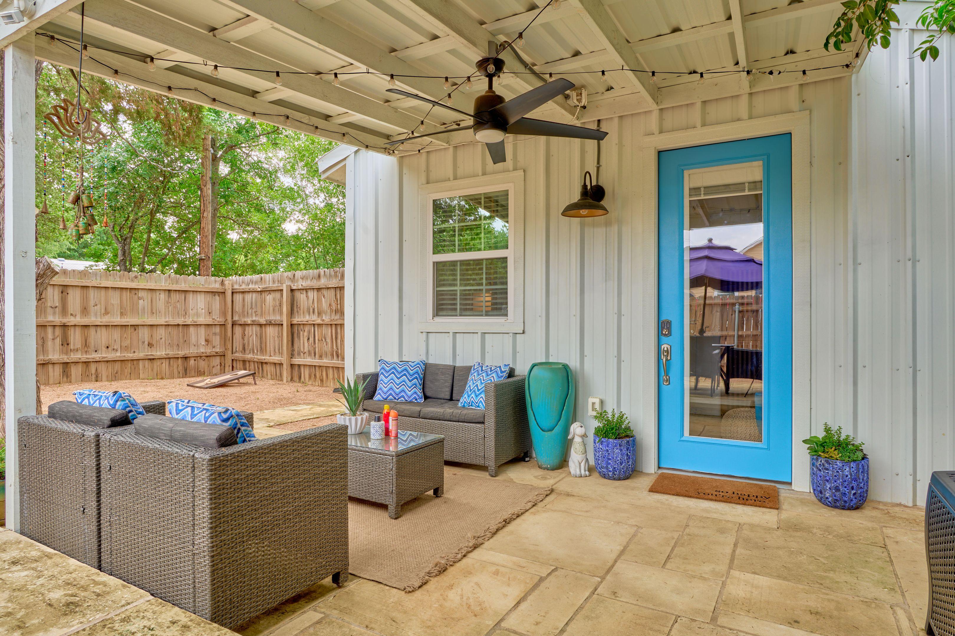 Covered porch with wicker seating beside a bright blue door — Hospitality & leisure photography, Austin A covered porch with wicker seating beside a bright blue door.