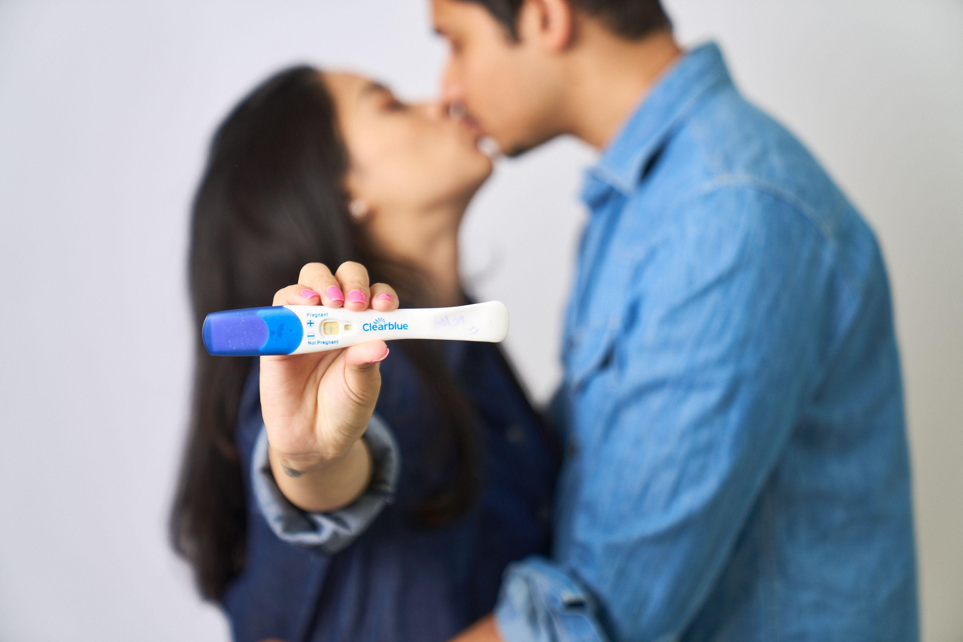 Couple kissing while holding a positive pregnancy test — Maternity photography, Austin Couple kissing while holding a positive pregnancy test