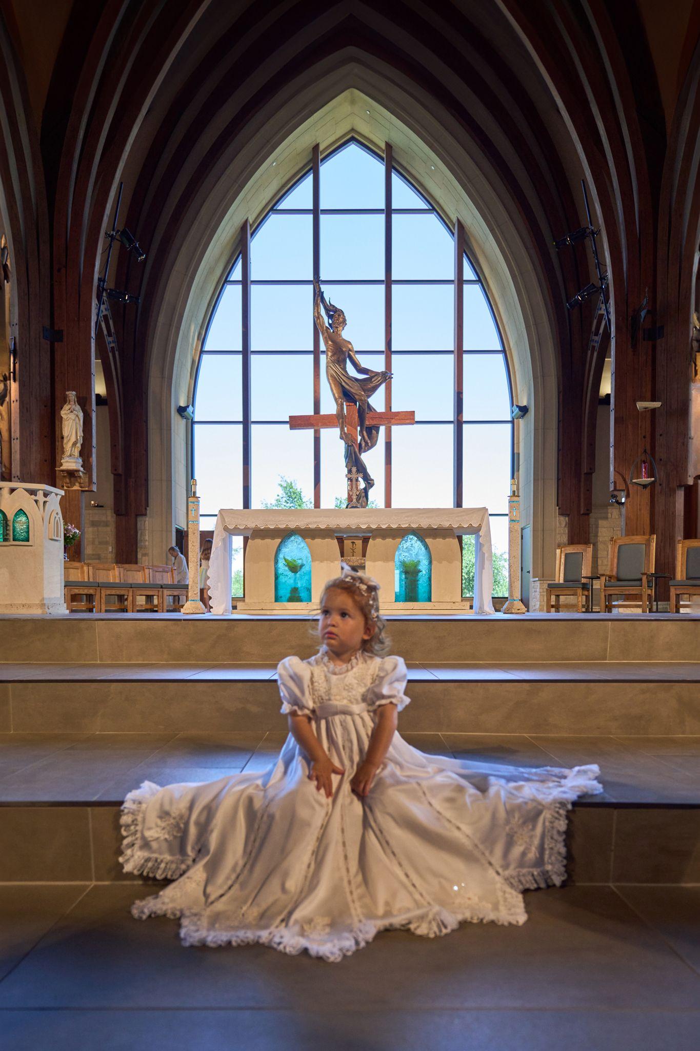 Young girl in a long ivory gown seated on the altar steps of a church — Religious Ceremonies photography, Austin A young girl in a long ivory gown seated on the altar steps of a church beneath a stained-glass window.