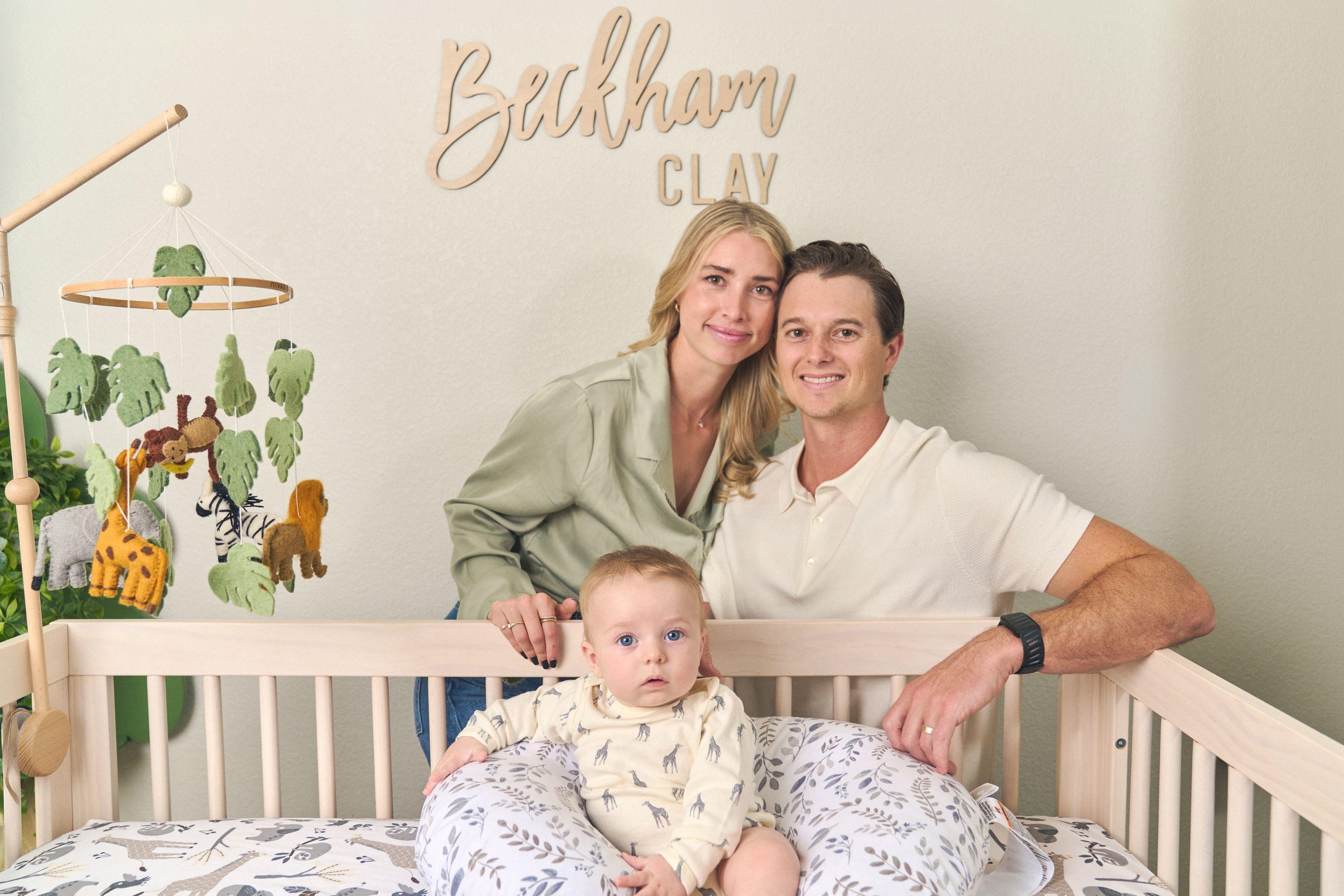 Parents standing behind a crib with their baby — Newborn photography, Austin Parents standing behind a crib with their baby, under wooden nursery lettering reading Beckham Clay.