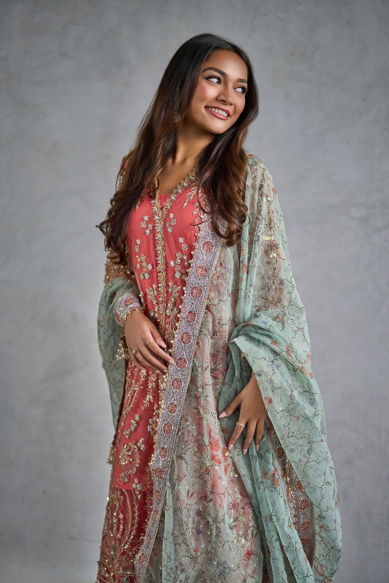 Model in a coral embroidered outfit standing full length against a gray backdrop — Photo retouching, Austin A model in a coral embroidered outfit standing full length against a gray backdrop.