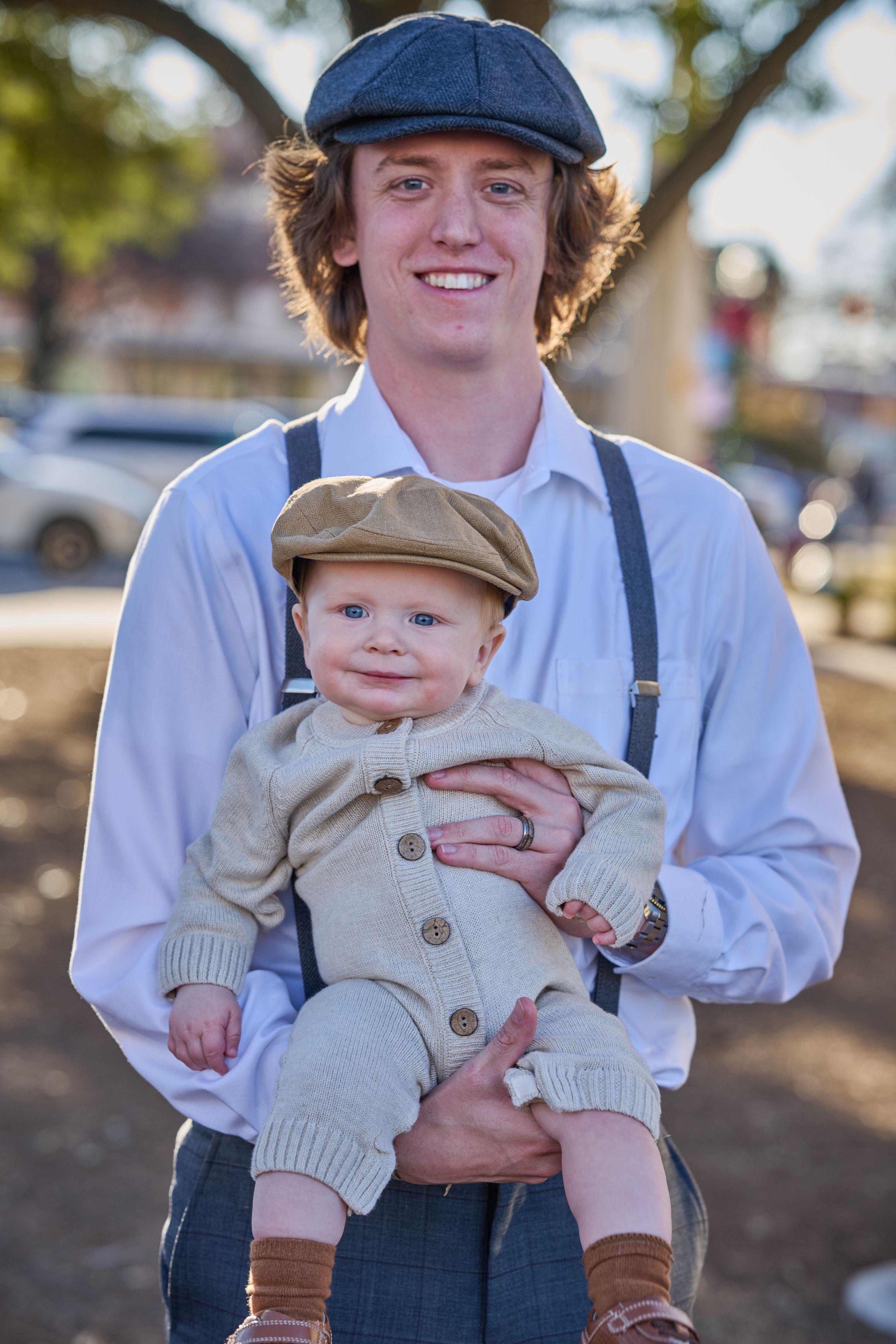 Young man in a newsboy cap and braces holding a baby in a matching cap on the Georgetown square — Georgetown Downtown photography, Austin A young man in a newsboy cap and braces holding a baby in a matching cap on the Georgetown square