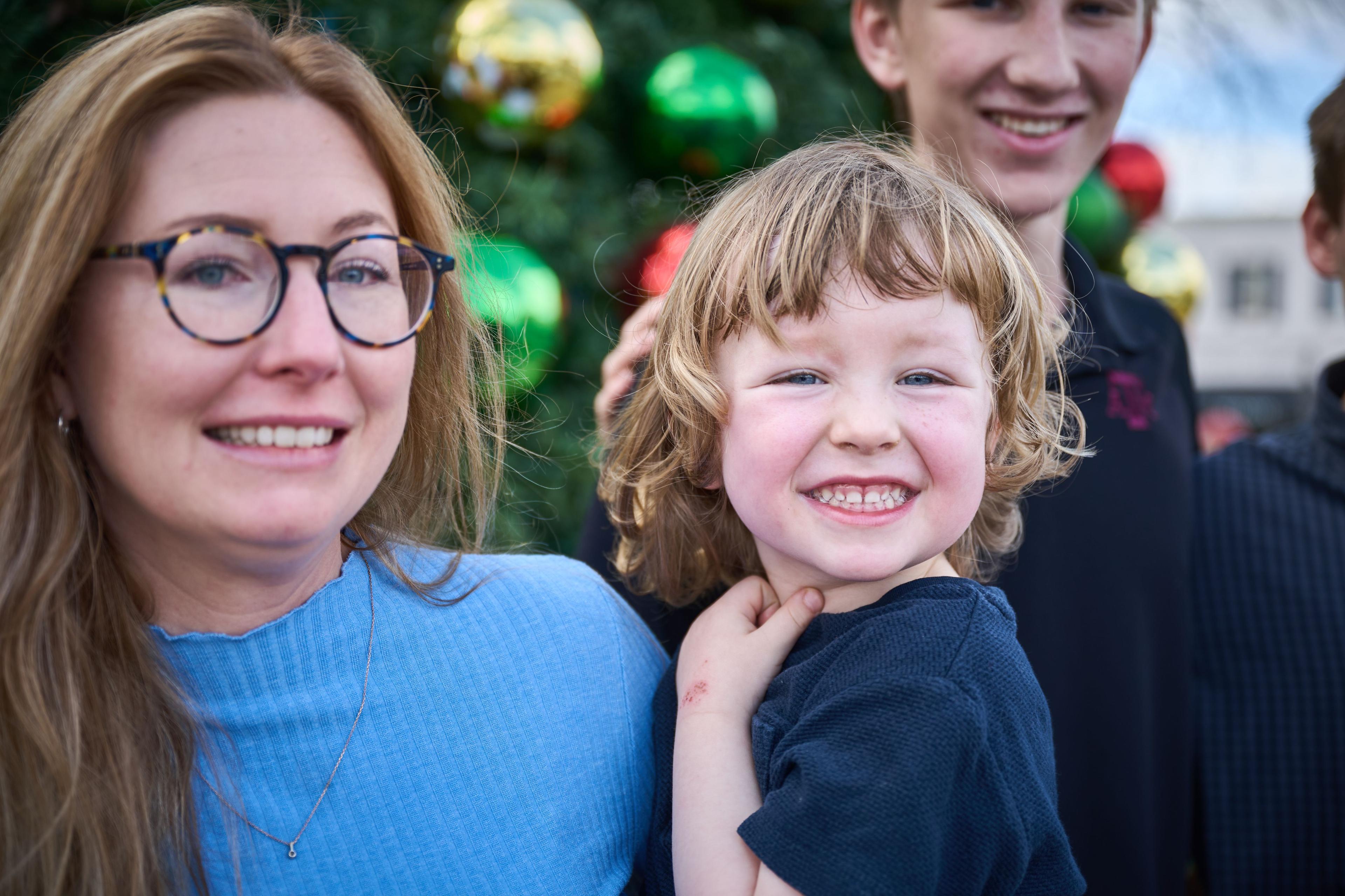 Mother and father either side of their laughing young son, Christmas lights — Georgetown Downtown photography, Austin A mother and father either side of their laughing young son, Christmas lights behind.
