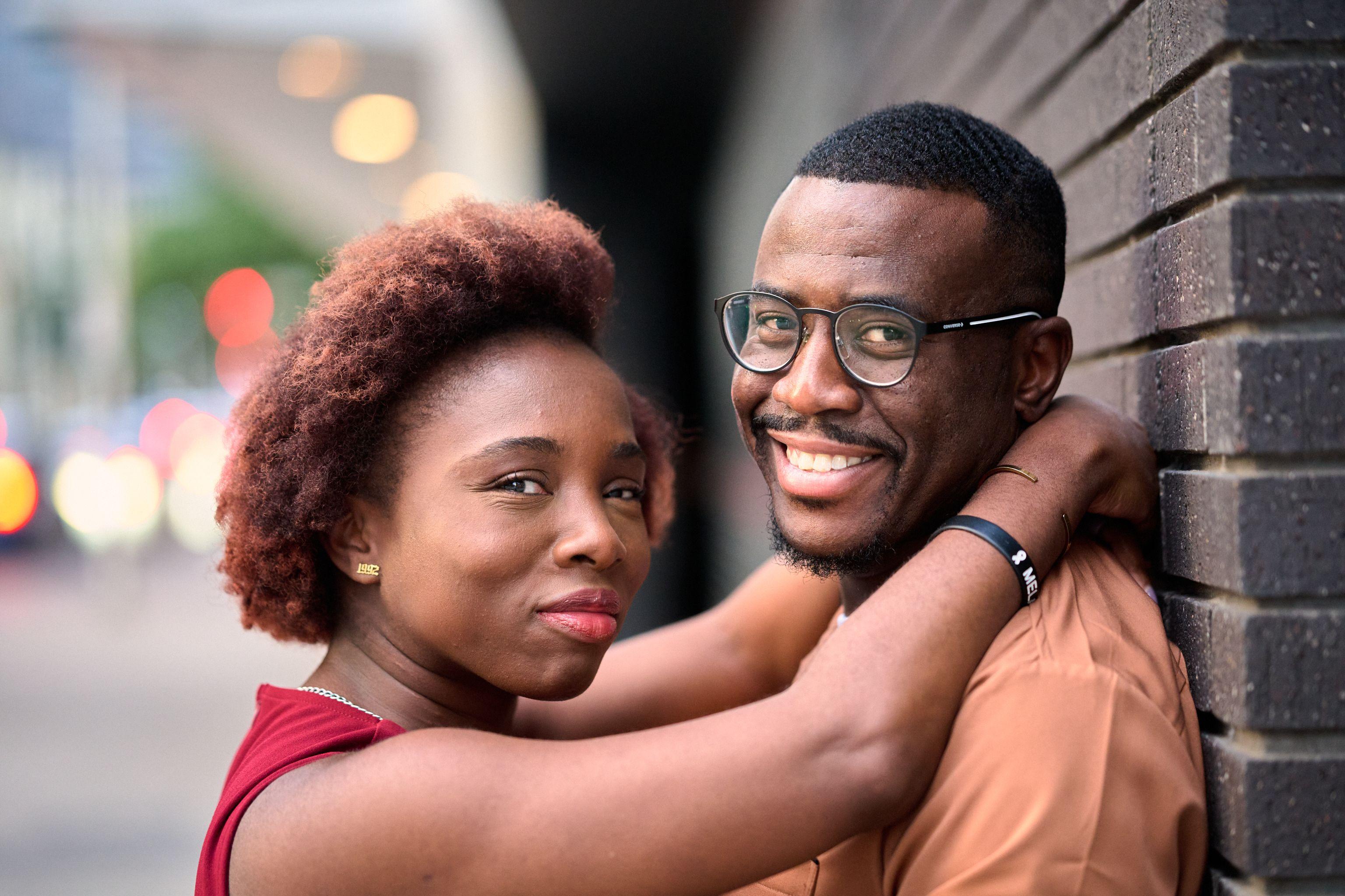 Couple embracing, her arm around his neck, both smiling to camera — Congress Avenue photography, Austin A couple embracing, her arm around his neck, both smiling to camera.