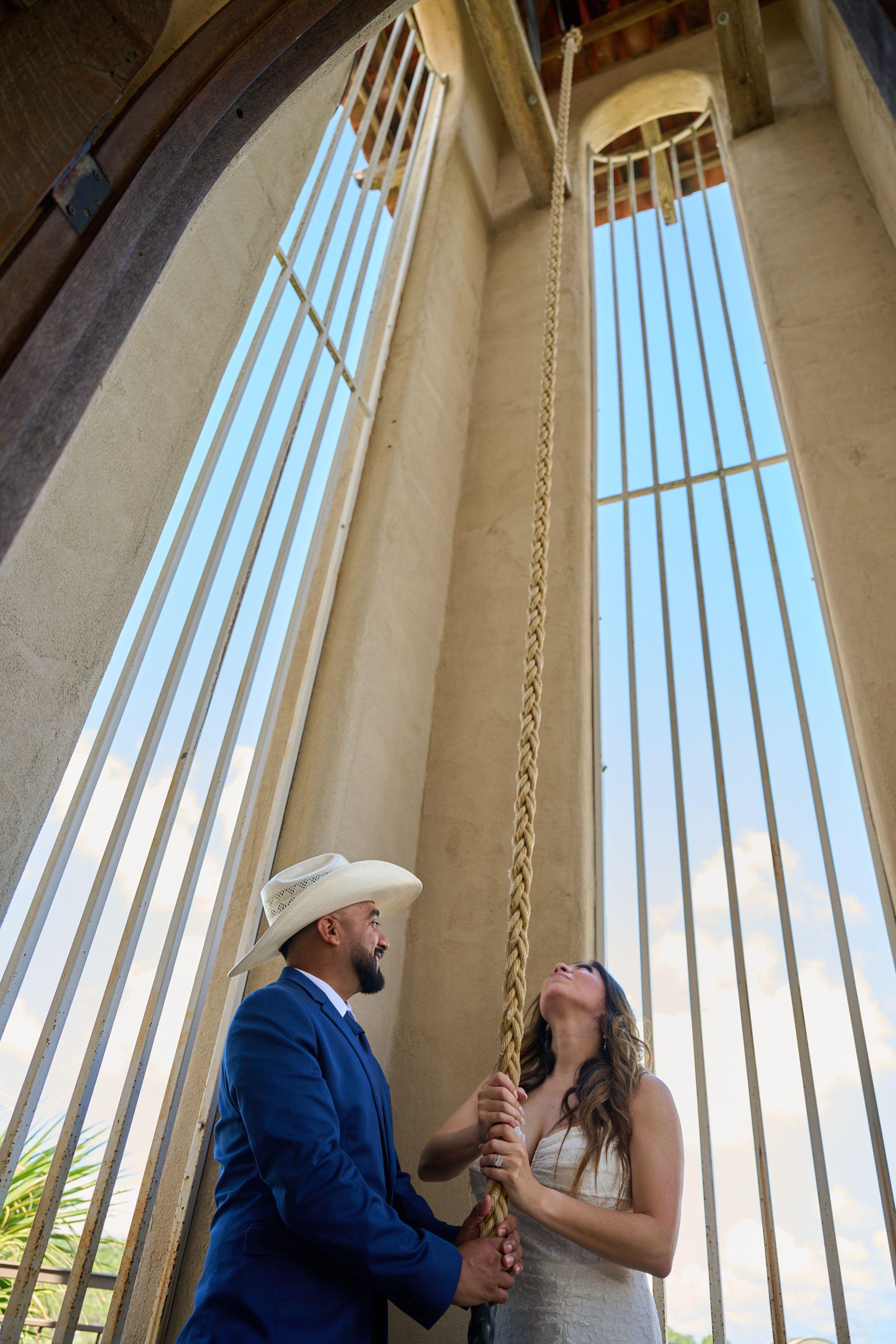 Couple pulling the bell rope together inside the open-sided hilltop chapel — Chapel Dulcinea photography, Austin A couple pulling the bell rope together inside the open-sided hilltop chapel.