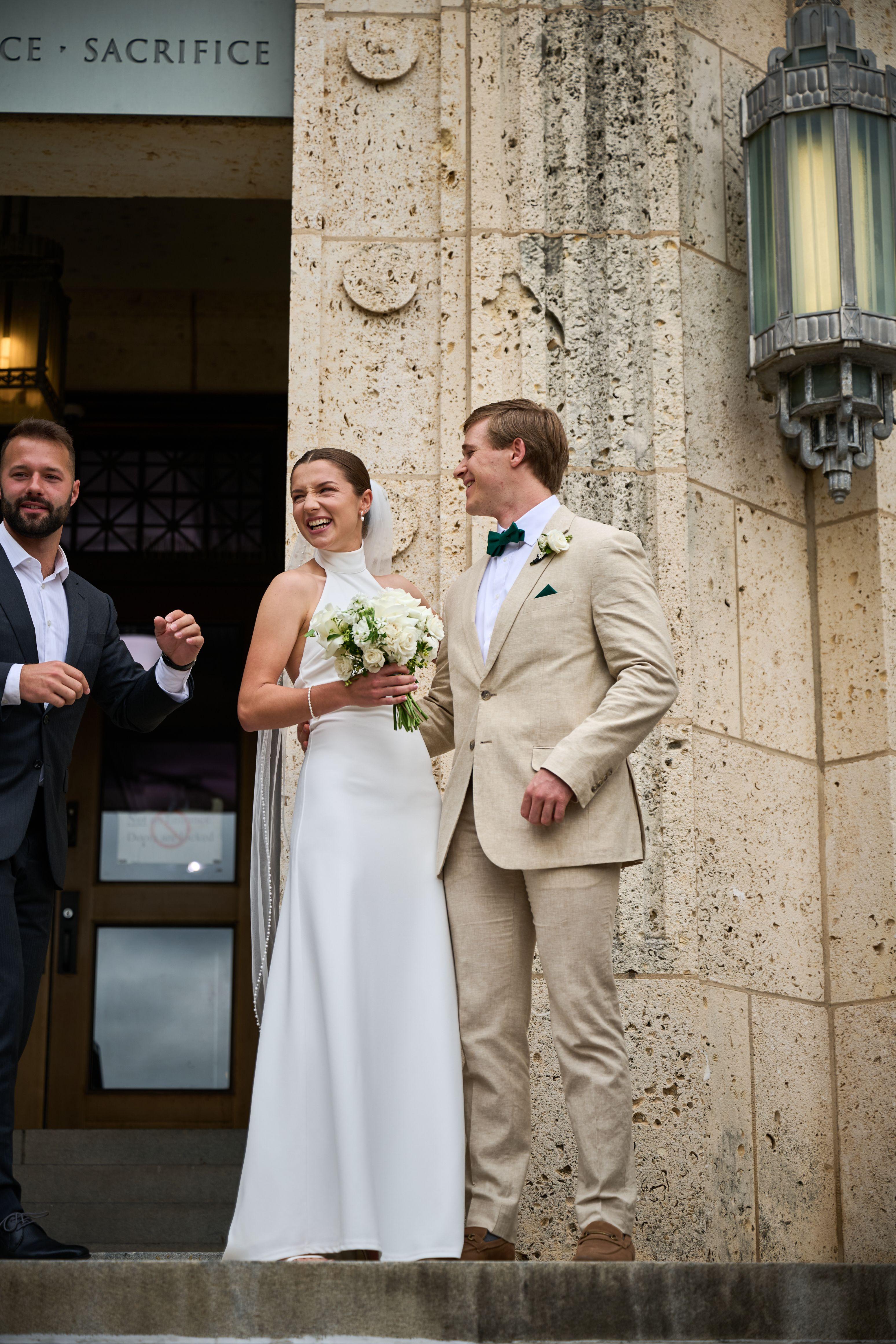 Bride and groom standing in a stone courthouse doorway, a witness beside them — Elopements photography, Austin A bride and groom standing in a stone courthouse doorway, a witness beside them.