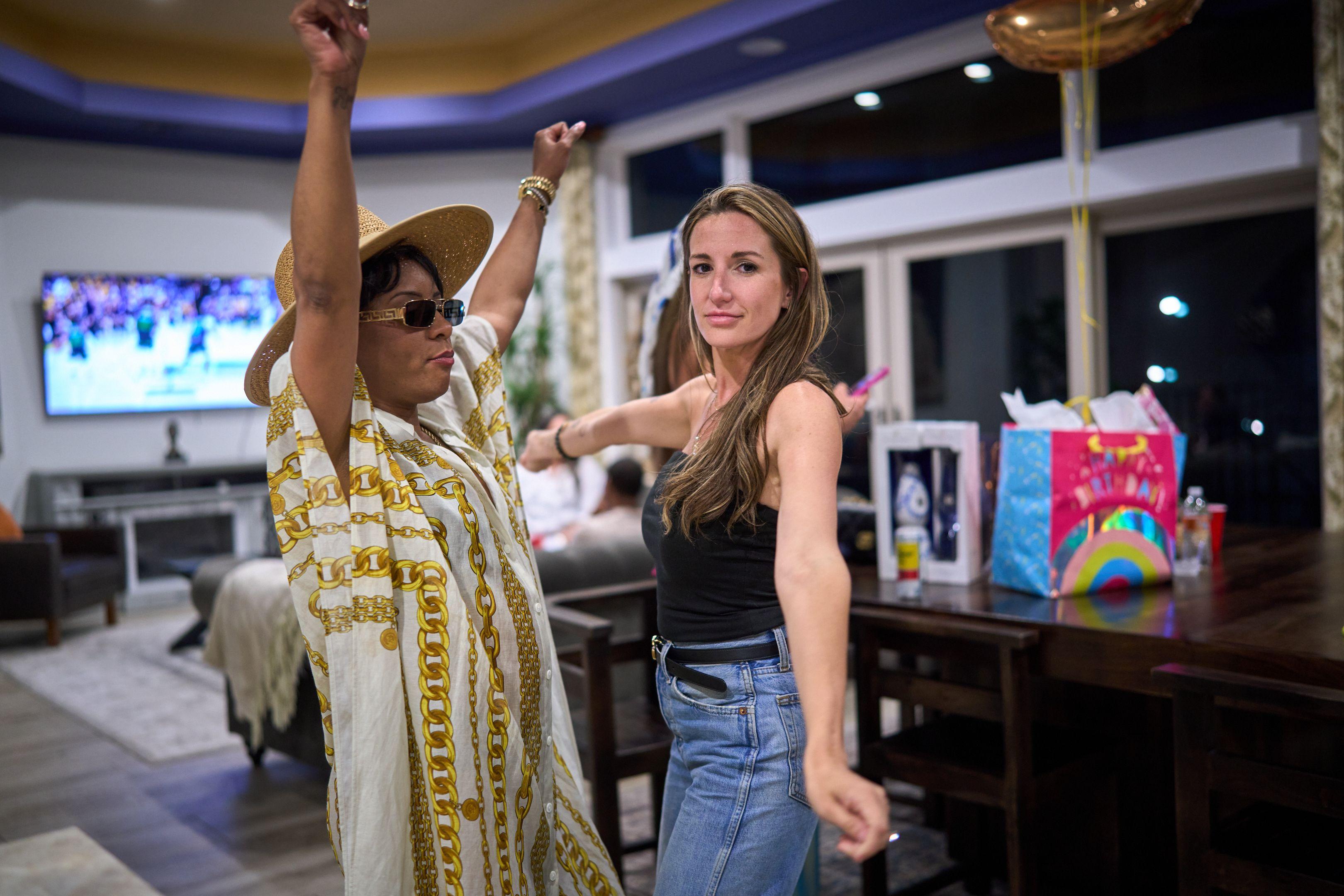 Two women dancing with arms raised on a covered patio — Party & nightlife photography, Austin Two women dancing with arms raised on a covered patio.