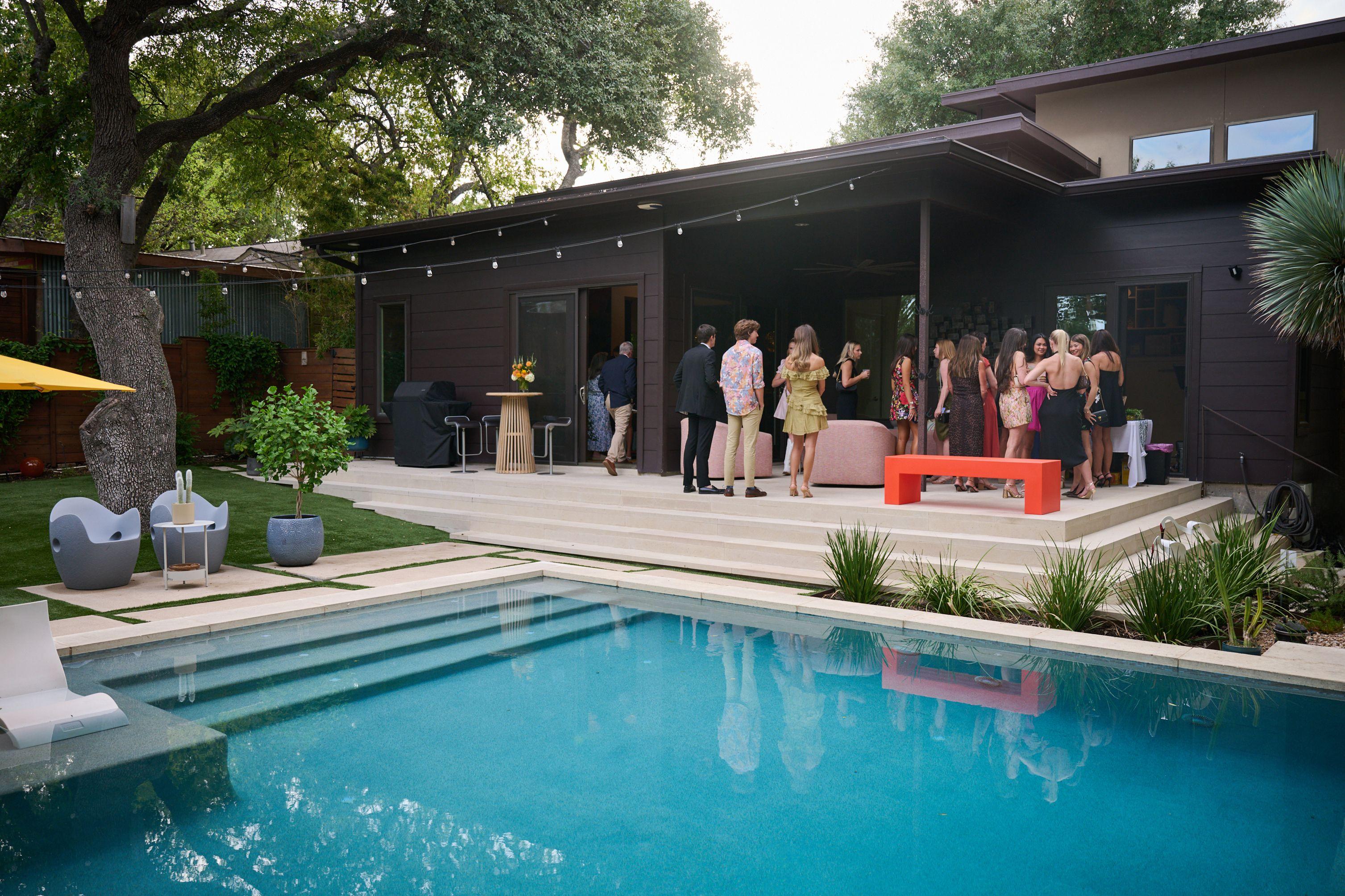 Backyard party seen across a lit swimming pool, guests gathered on the terrace beyond — Formal Celebrations photography, Austin A backyard party seen across a lit swimming pool, guests gathered on the terrace beyond.