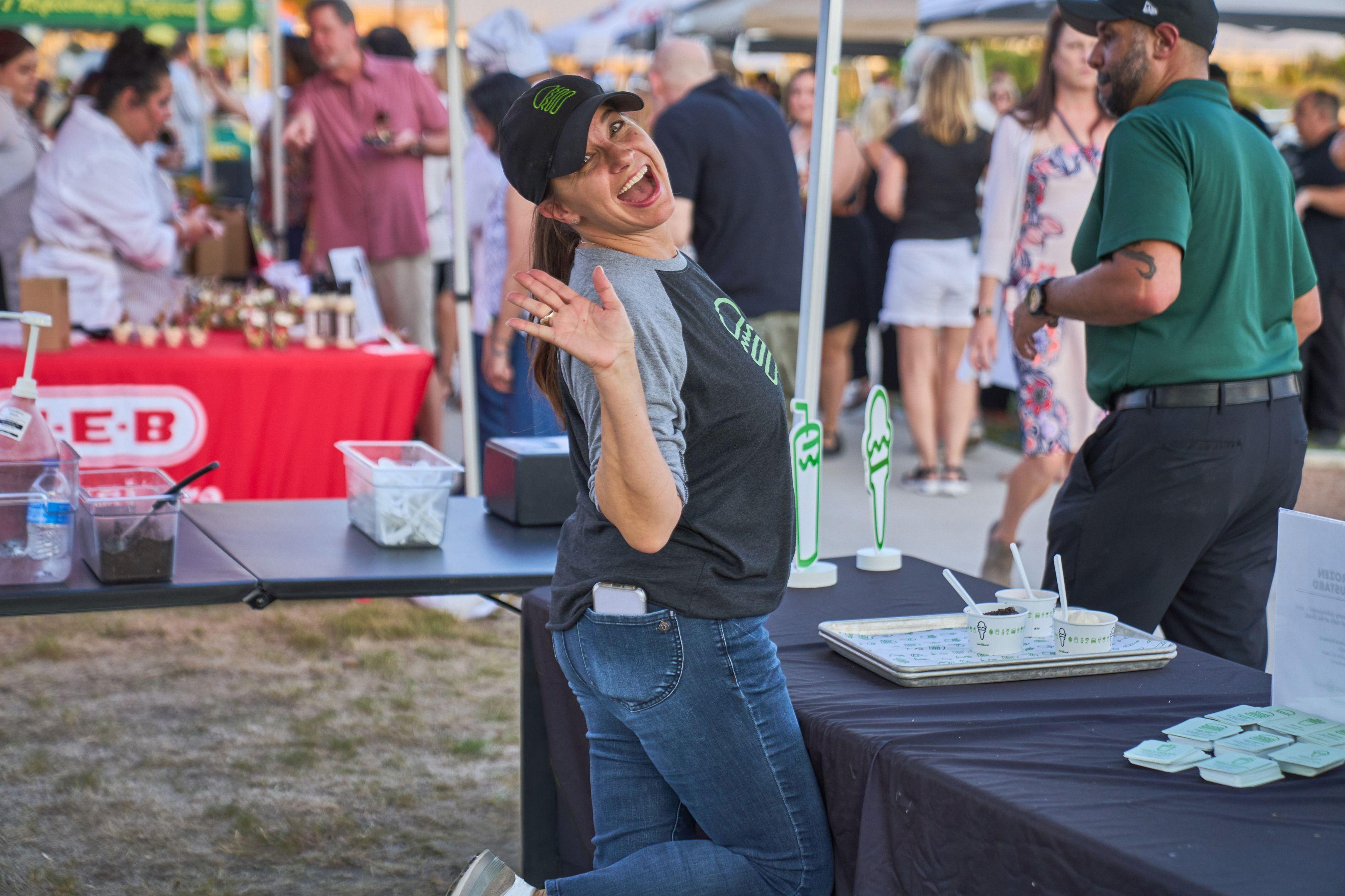 Festival-goer laughing at a tasting booth with a drink in hand — Festival photography, Austin A festival-goer laughing at a tasting booth with a drink in hand.