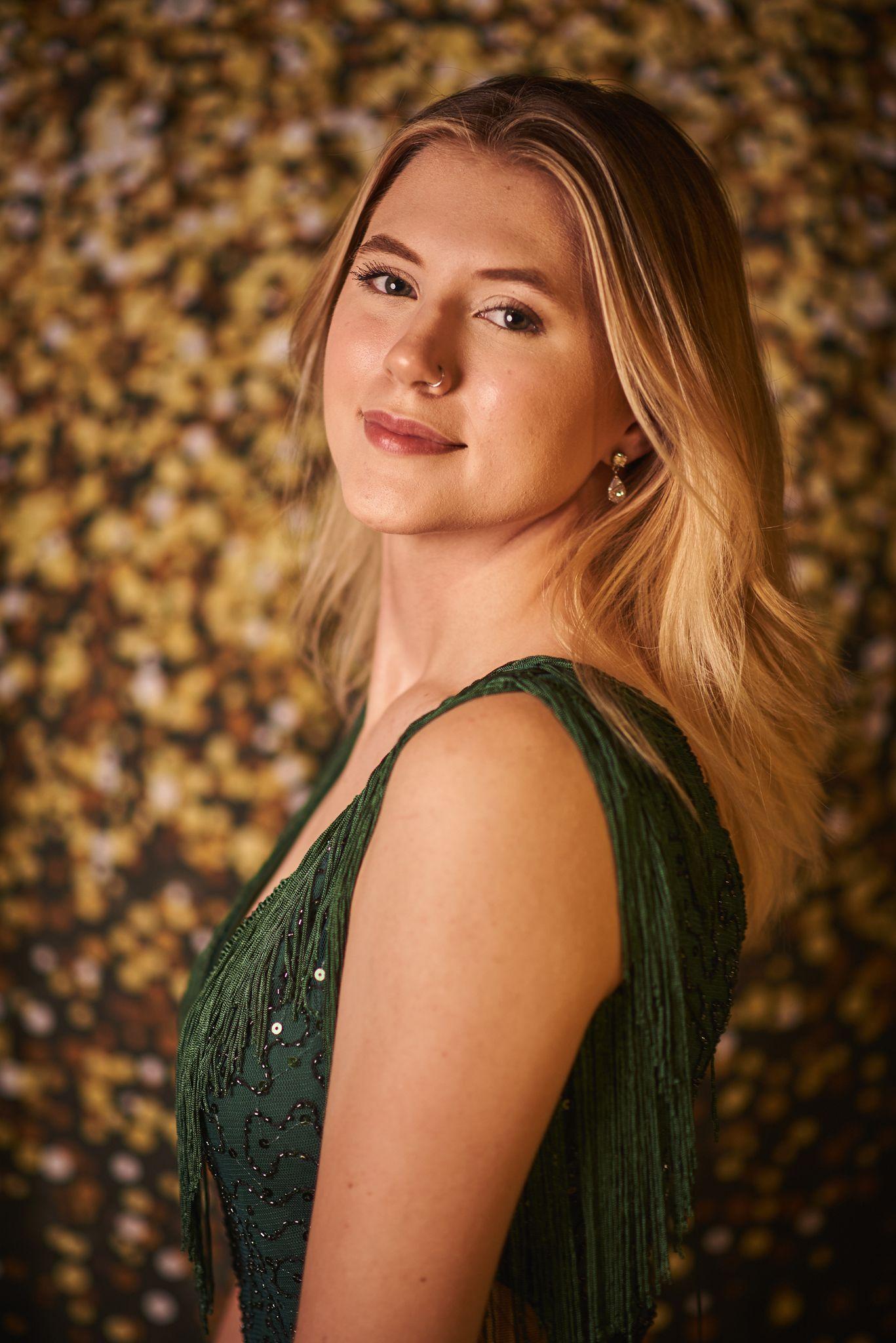 Woman in a green fringed top against a wall of golden bokeh — Portrait photography, Austin A woman in a green fringed top against a wall of golden bokeh.