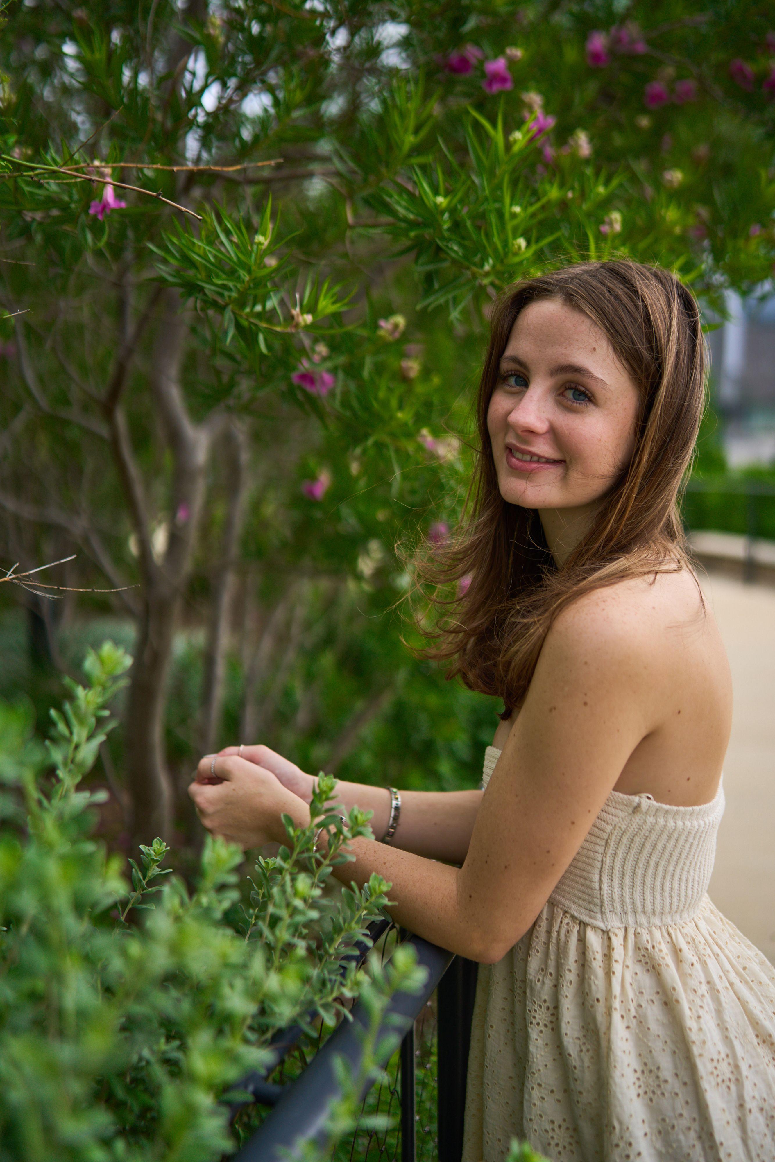 Young woman in a cream dress touching a flowering shrub, looking to camera — Waterloo Park photography, Austin A young woman in a cream dress touching a flowering shrub, looking to camera.