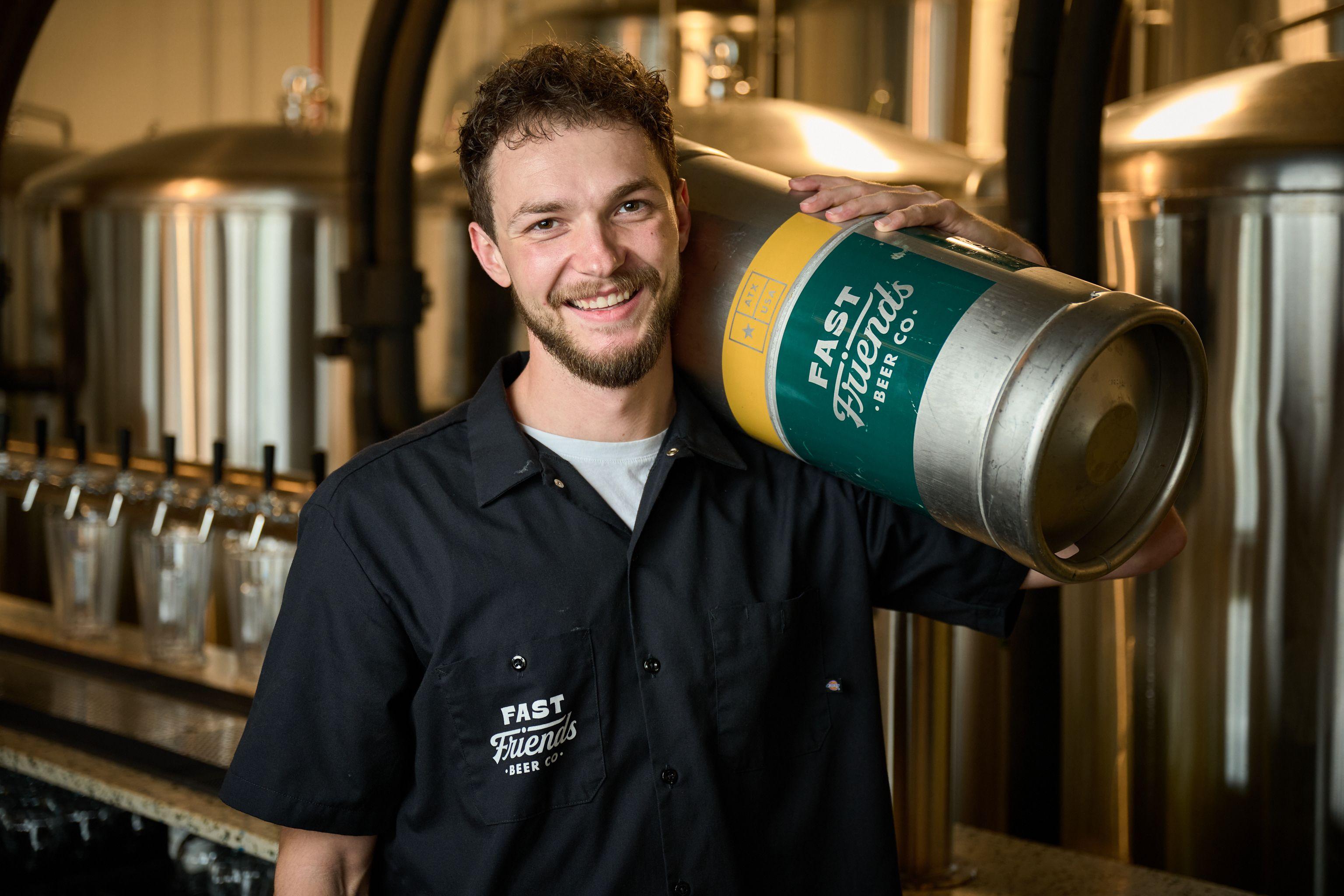 Brewery worker in a branded black shirt carrying a keg on his shoulder — Brand Collaborations photography, Austin Brewery worker in a branded black shirt carrying a keg on his shoulder