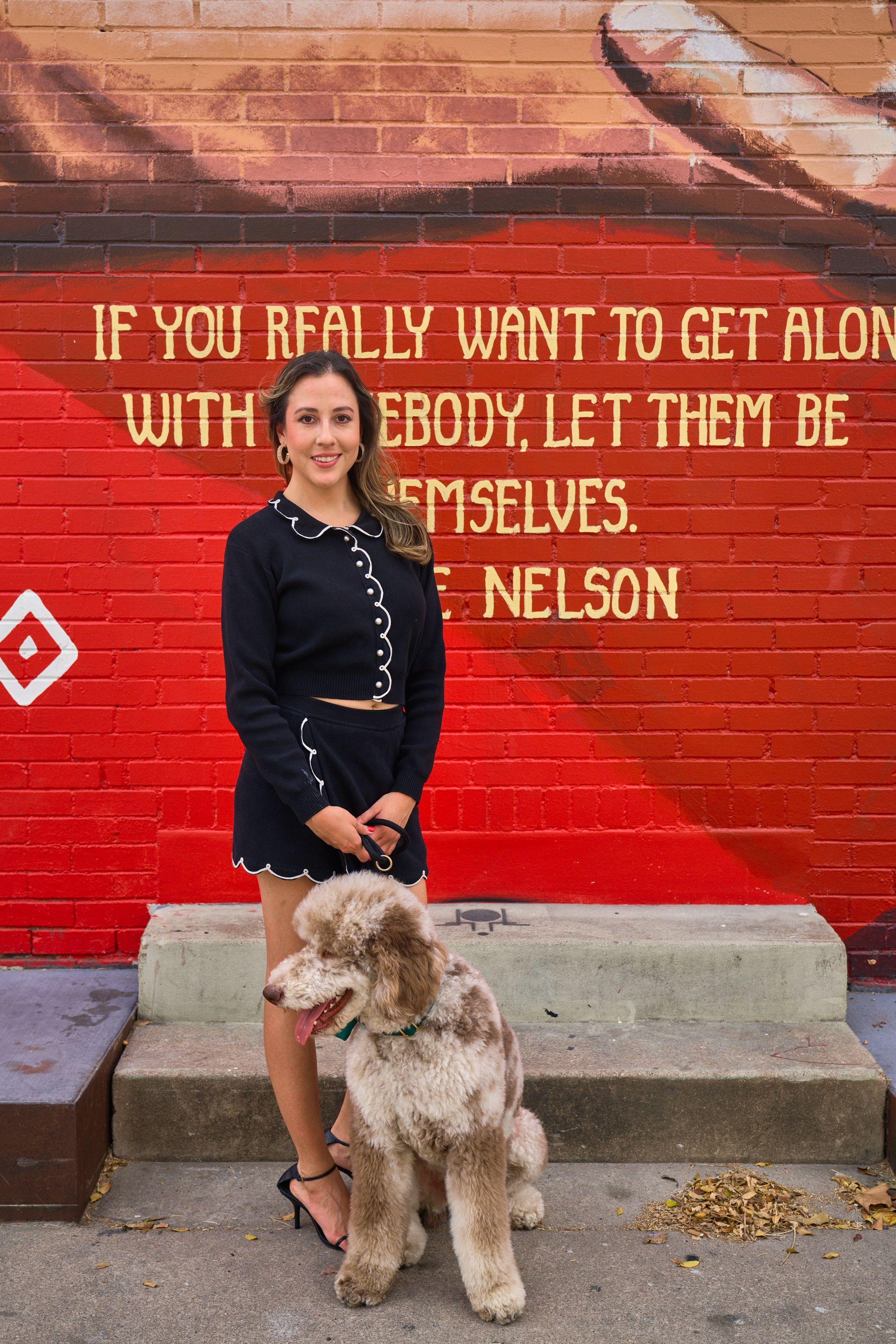 Woman with a labradoodle in front of a red mural carrying a Willie Nelson quote — South Congress (SoCo) photography, Austin A woman with a labradoodle in front of a red mural carrying a Willie Nelson quote on South Congress.