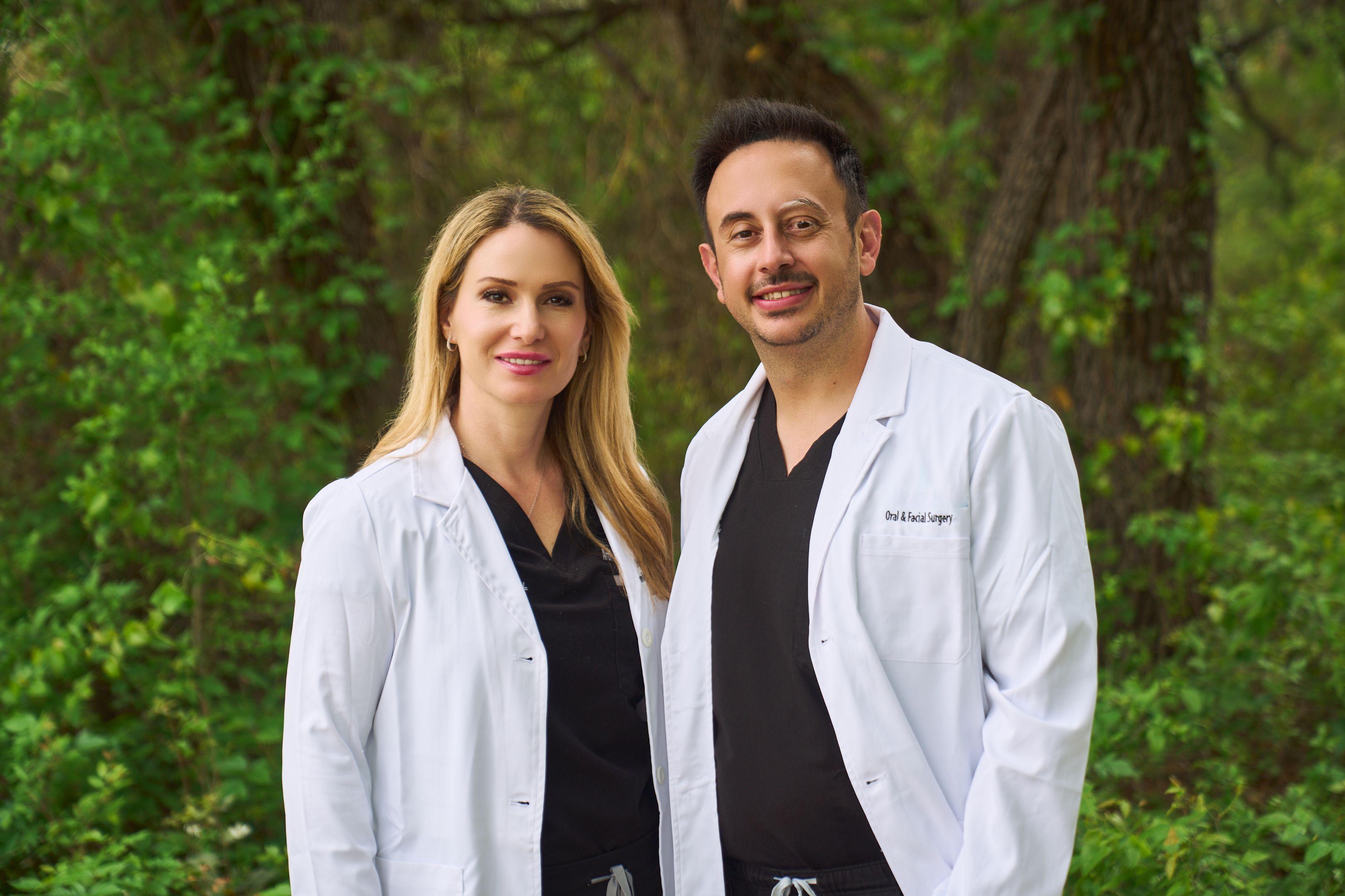 Two clinicians in white coats standing together outdoors in front of greenery — Medical team photography, Austin Two clinicians in white coats standing together outdoors in front of greenery