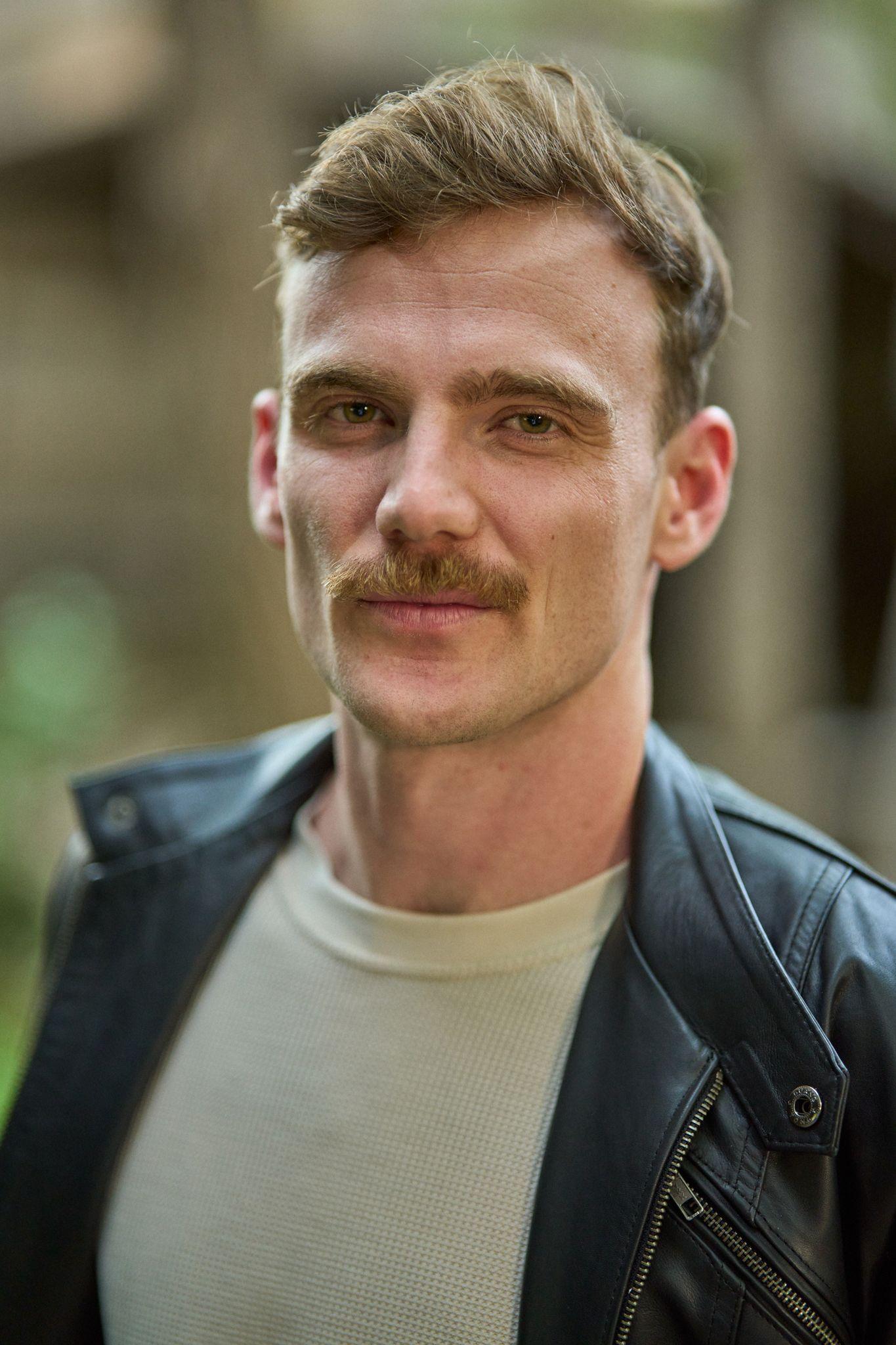 Close portrait of a man in a leather jacket against soft green foliage — Waterloo Park photography, Austin A close portrait of a man in a leather jacket against soft green foliage.