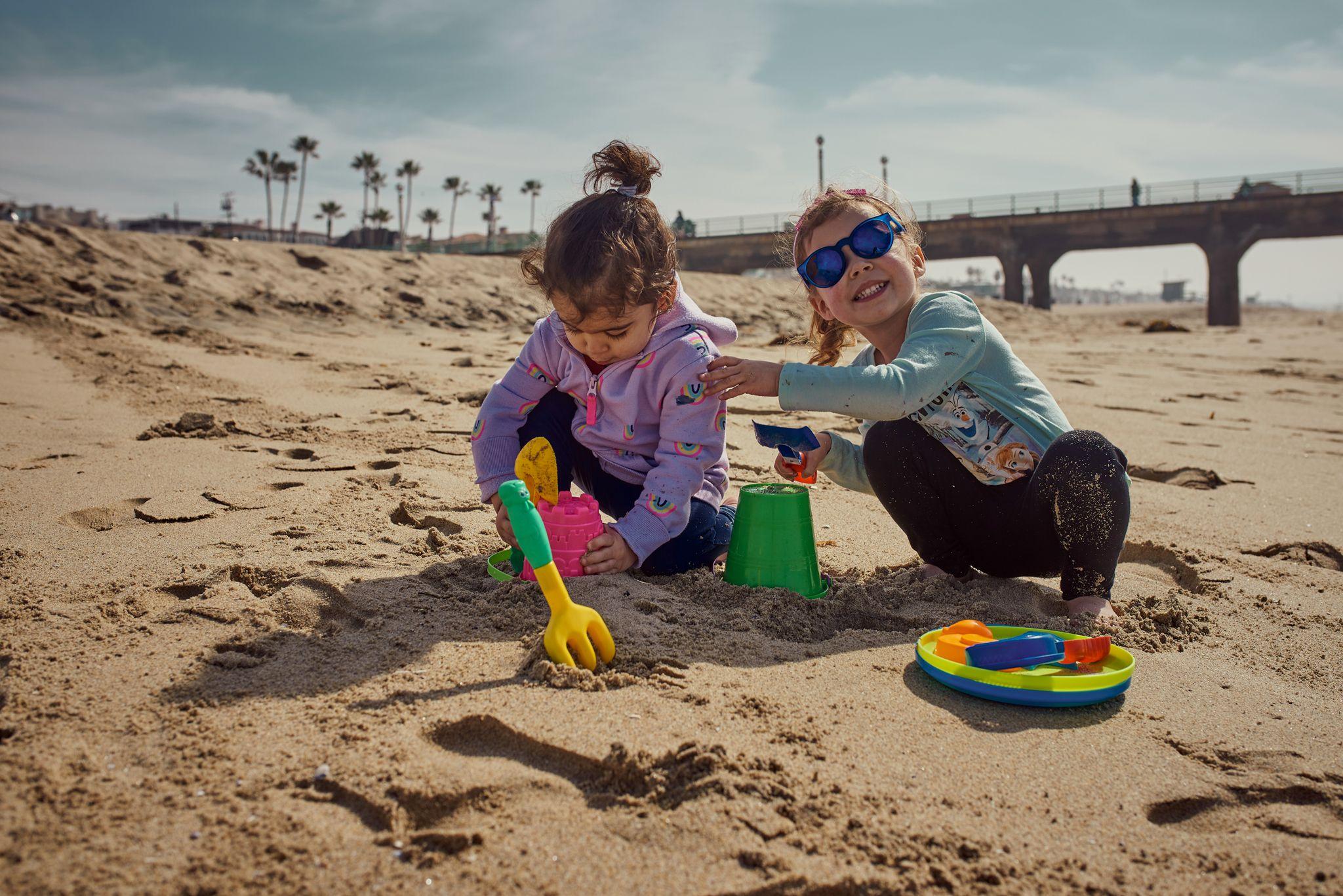 Two small children digging with plastic spades in the sand — Family Portraits photography, Austin Two small children digging with plastic spades in the sand.