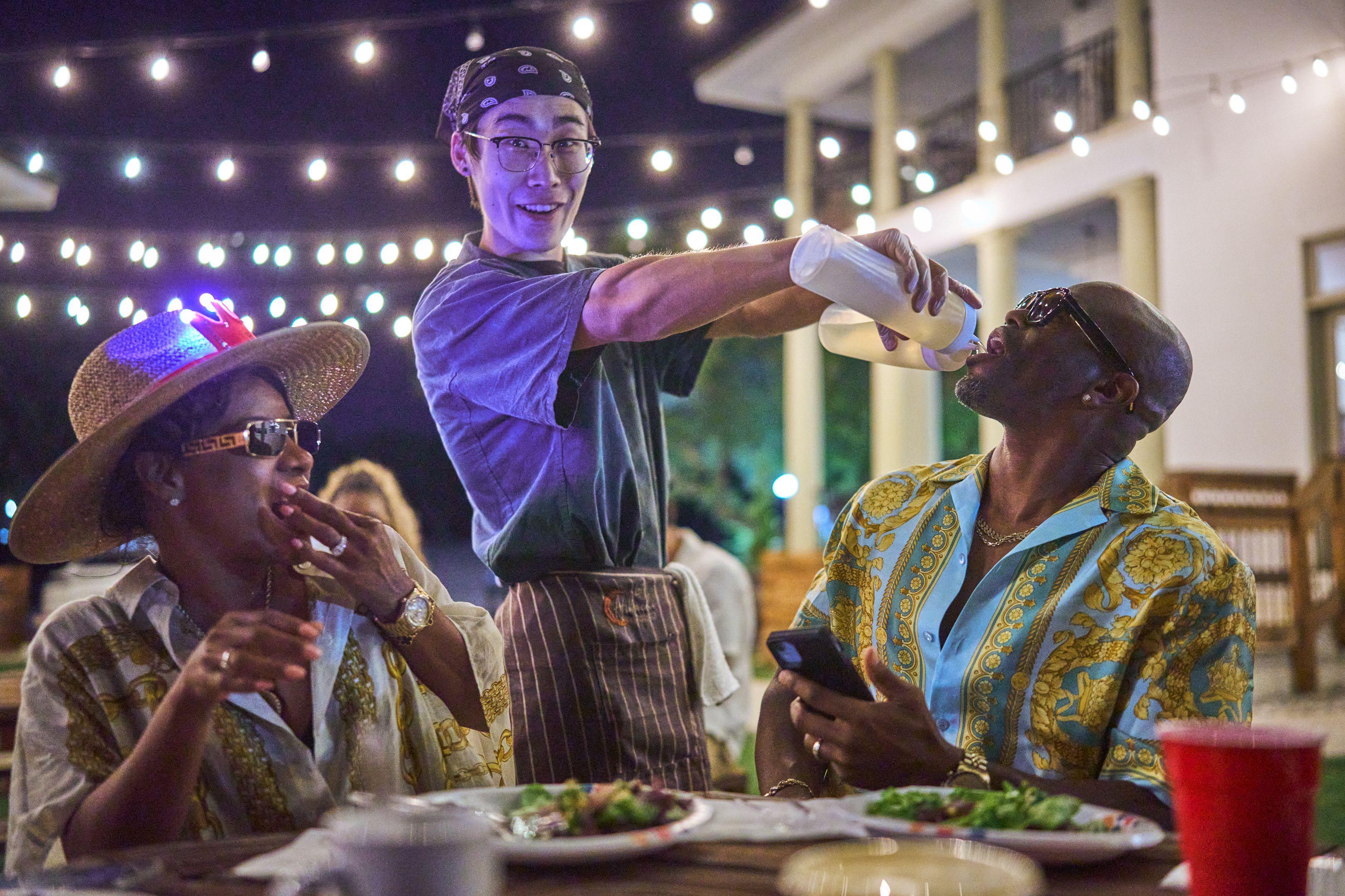 Server pouring a drink for guests under string lights at an outdoor party — Party & nightlife photography, Austin A server pouring a drink for guests under string lights at an outdoor party.