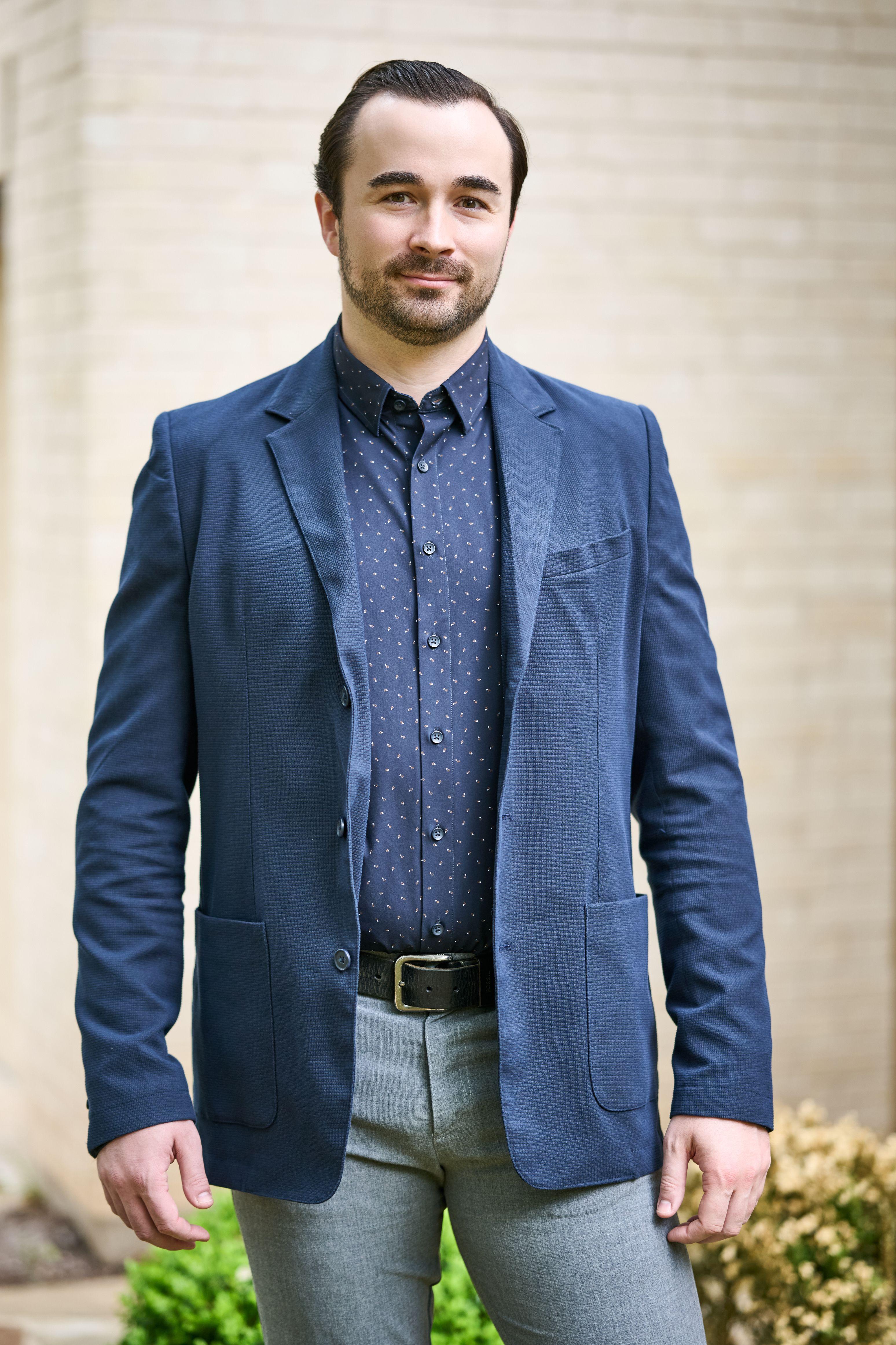 Man in a blue blazer and patterned shirt standing outdoors in front of a pale brick wall — Business headshots, Austin A man in a blue blazer and patterned shirt standing outdoors in front of a pale brick wall