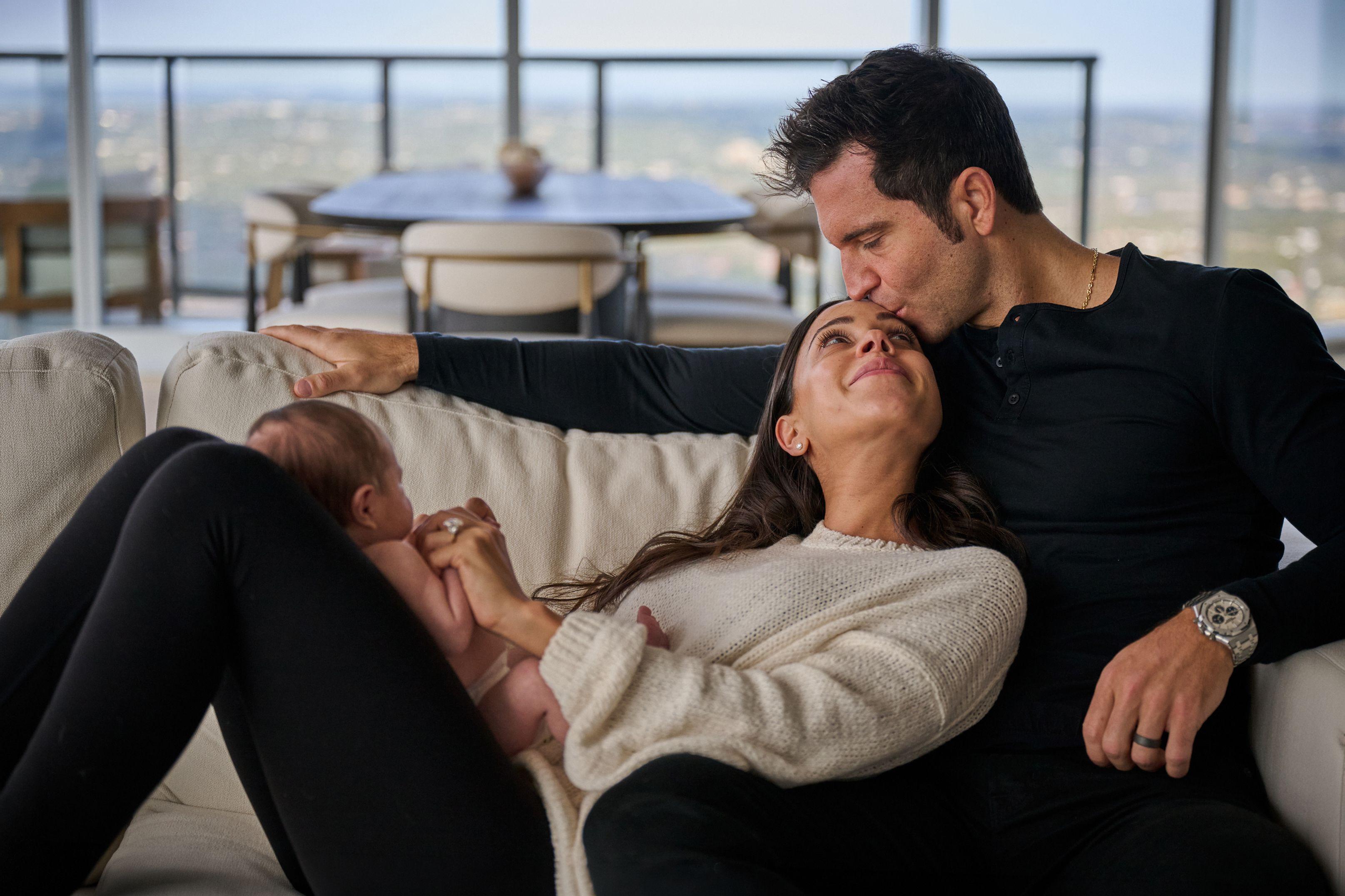 Father kissing the mother's forehead as she holds their newborn — Newborn photography, Austin A father kissing the mother's forehead as she holds their newborn.